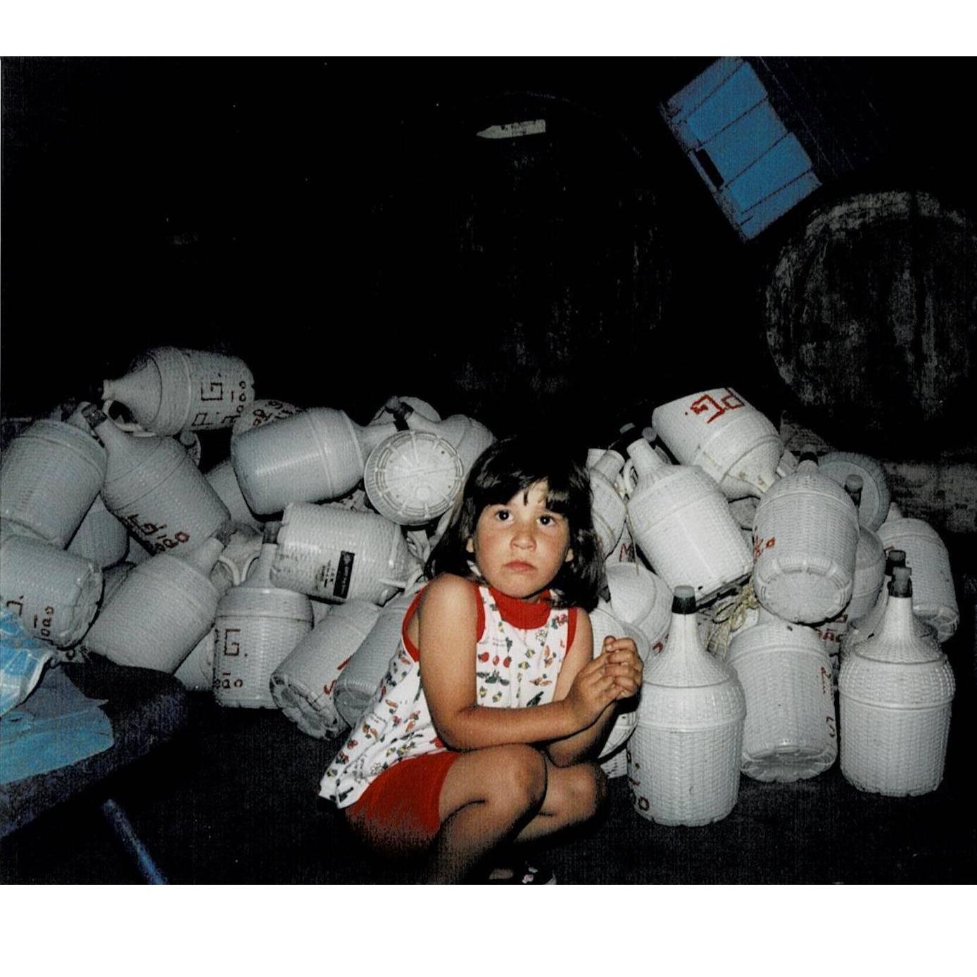 Young Marina sad and surrounded by empty bottles. She's getting to know the inner-workings of her grandfather's wine