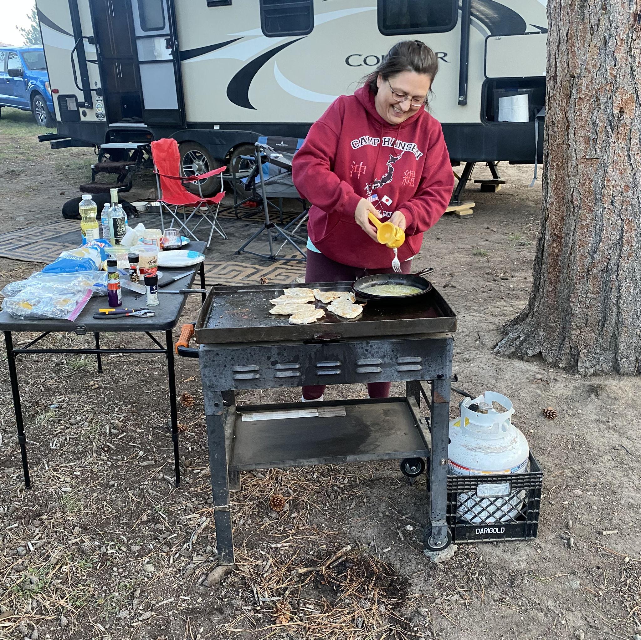 Claudia is in her element cooking by a campfire