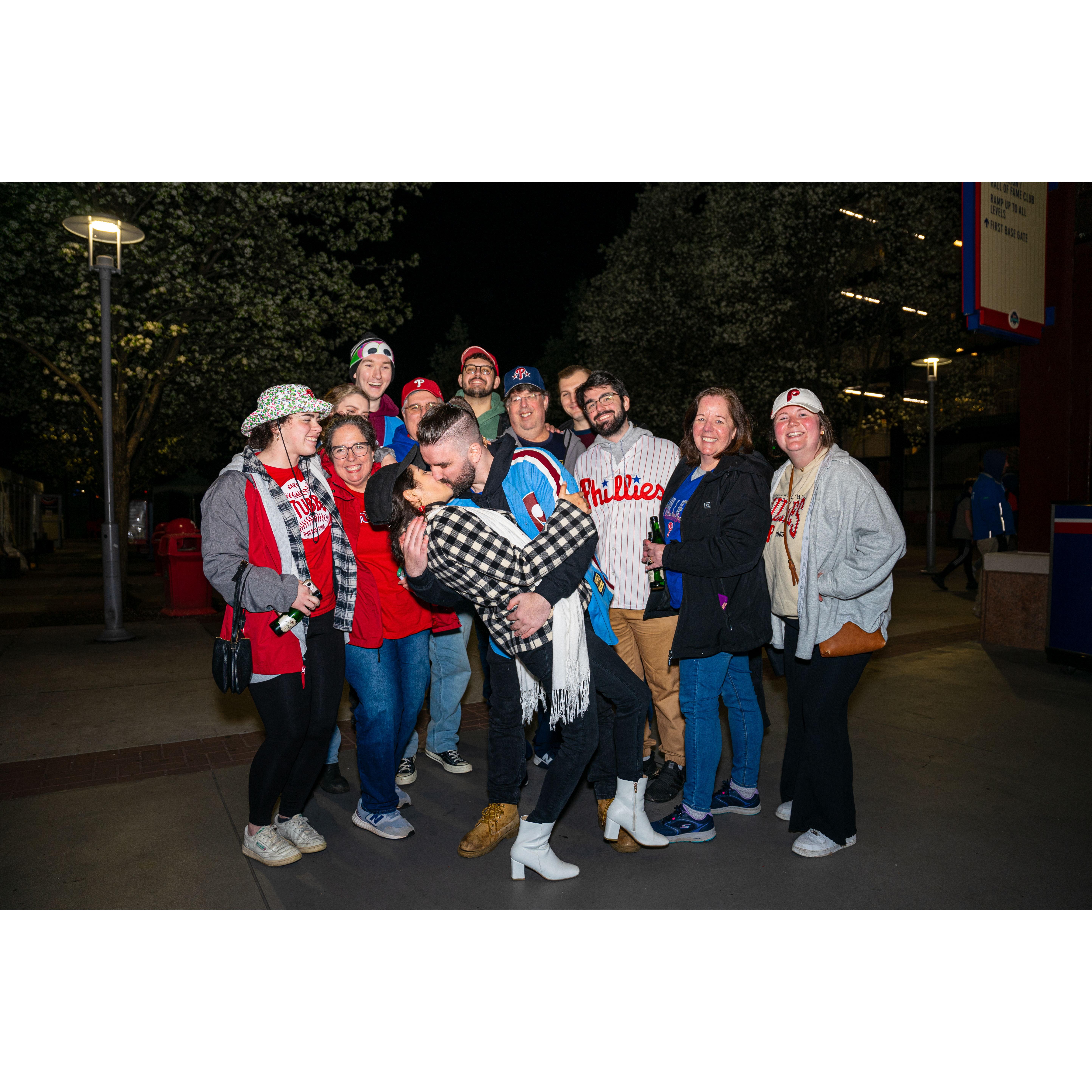 A group picture while the happy couple share a loving kiss.