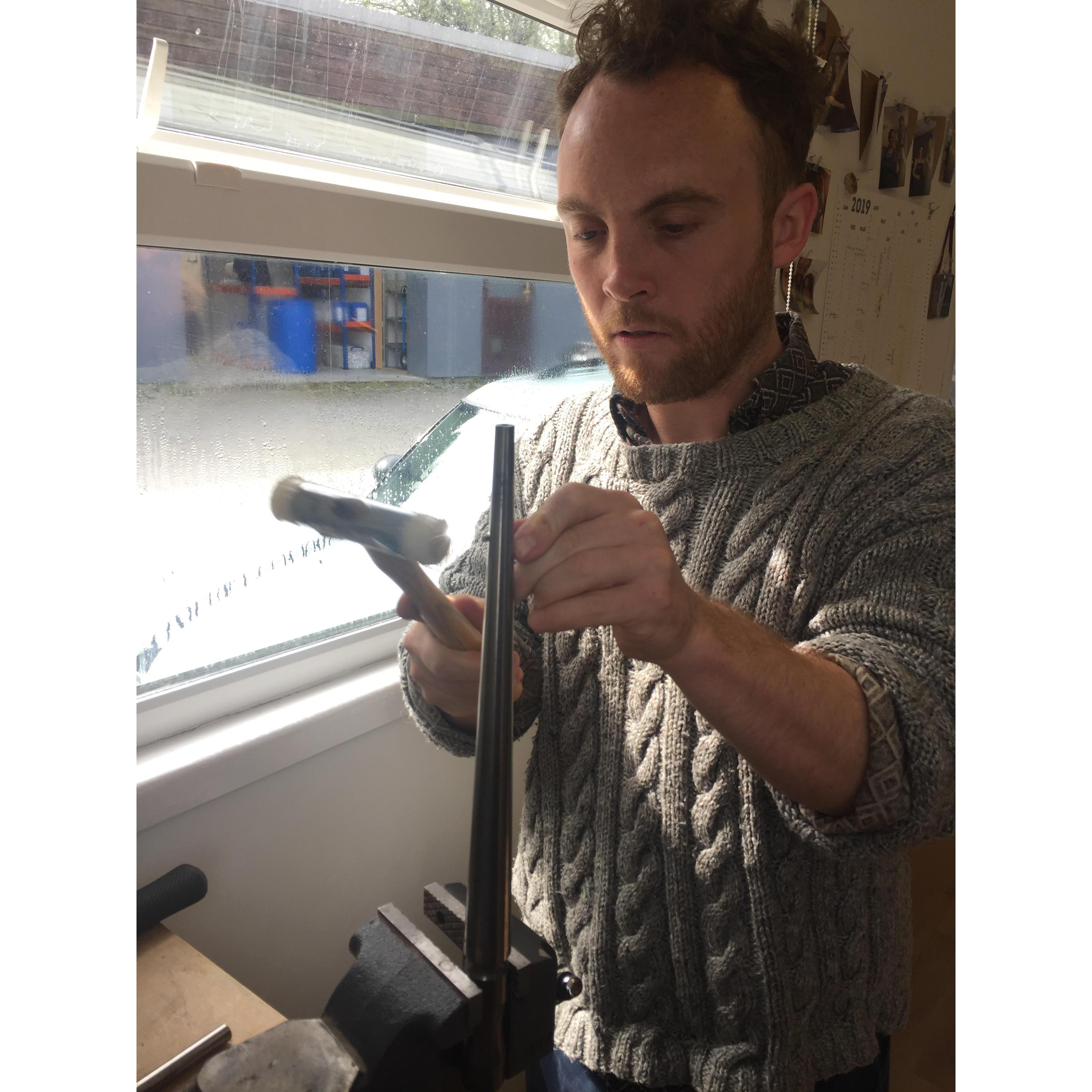 Hammering the straight sheet of metal into a ring shape