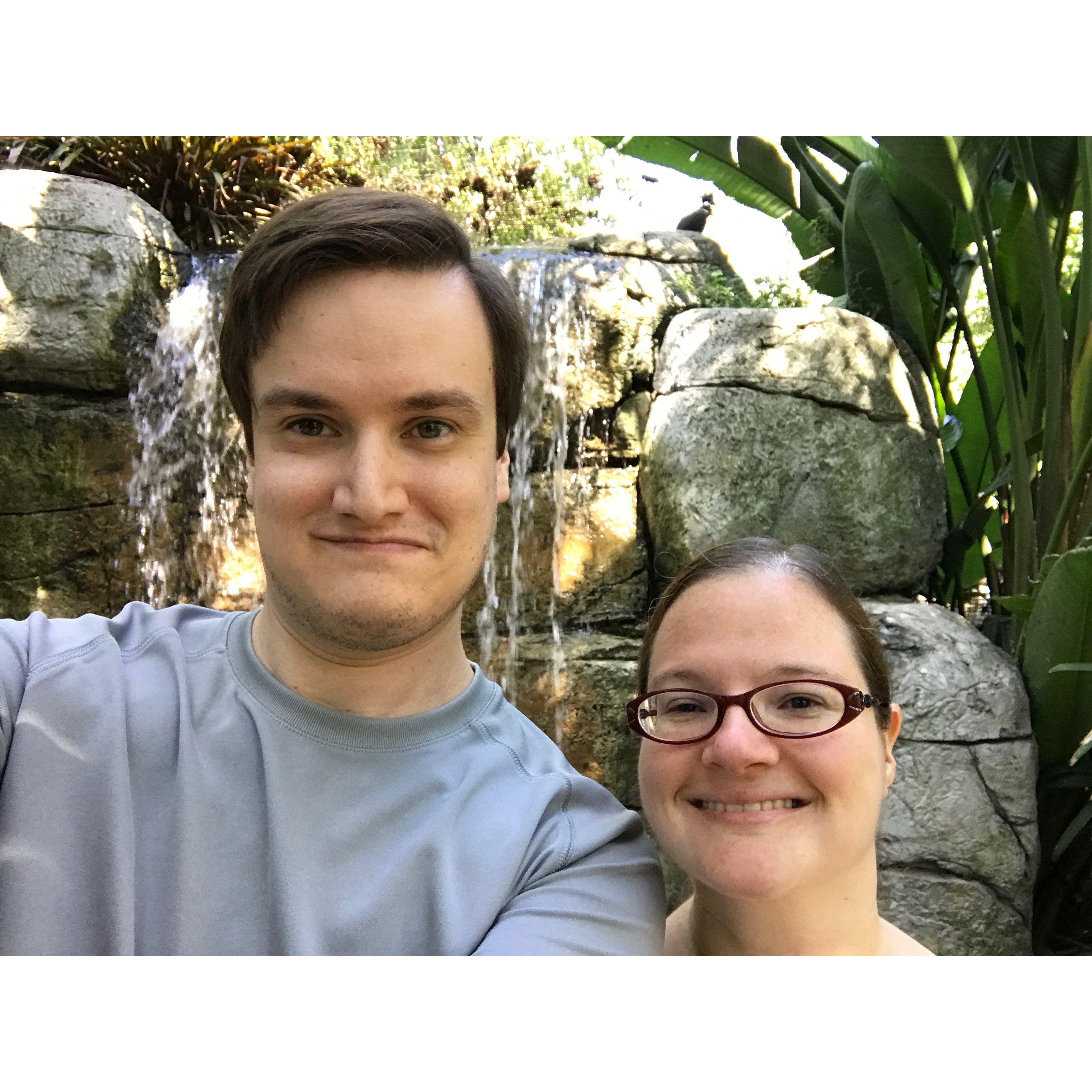 Olivia and Zac smiling in front of a waterfall.