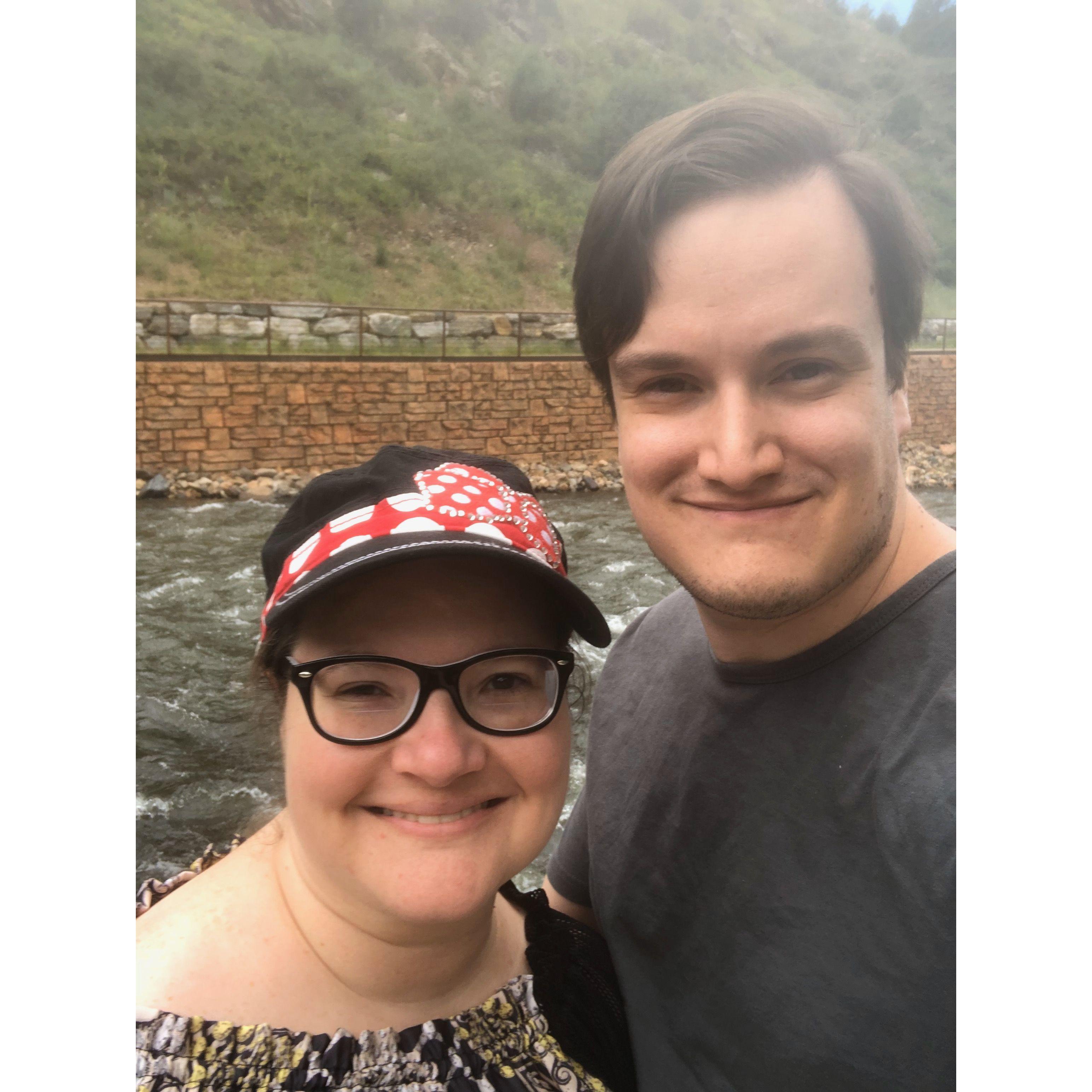 The couple smiling in front of river rapids with harsh waters