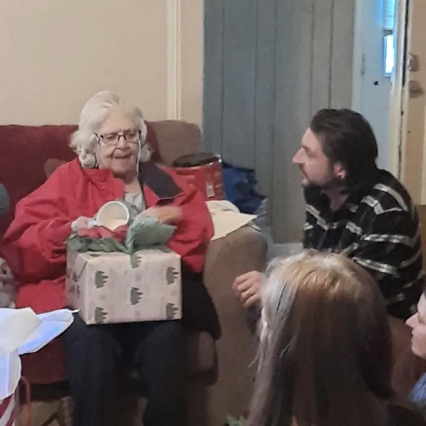The grooms grandmother (nanny) and his brother , Aubrey, and the bride all waiting for nanny to open her Christmas gift