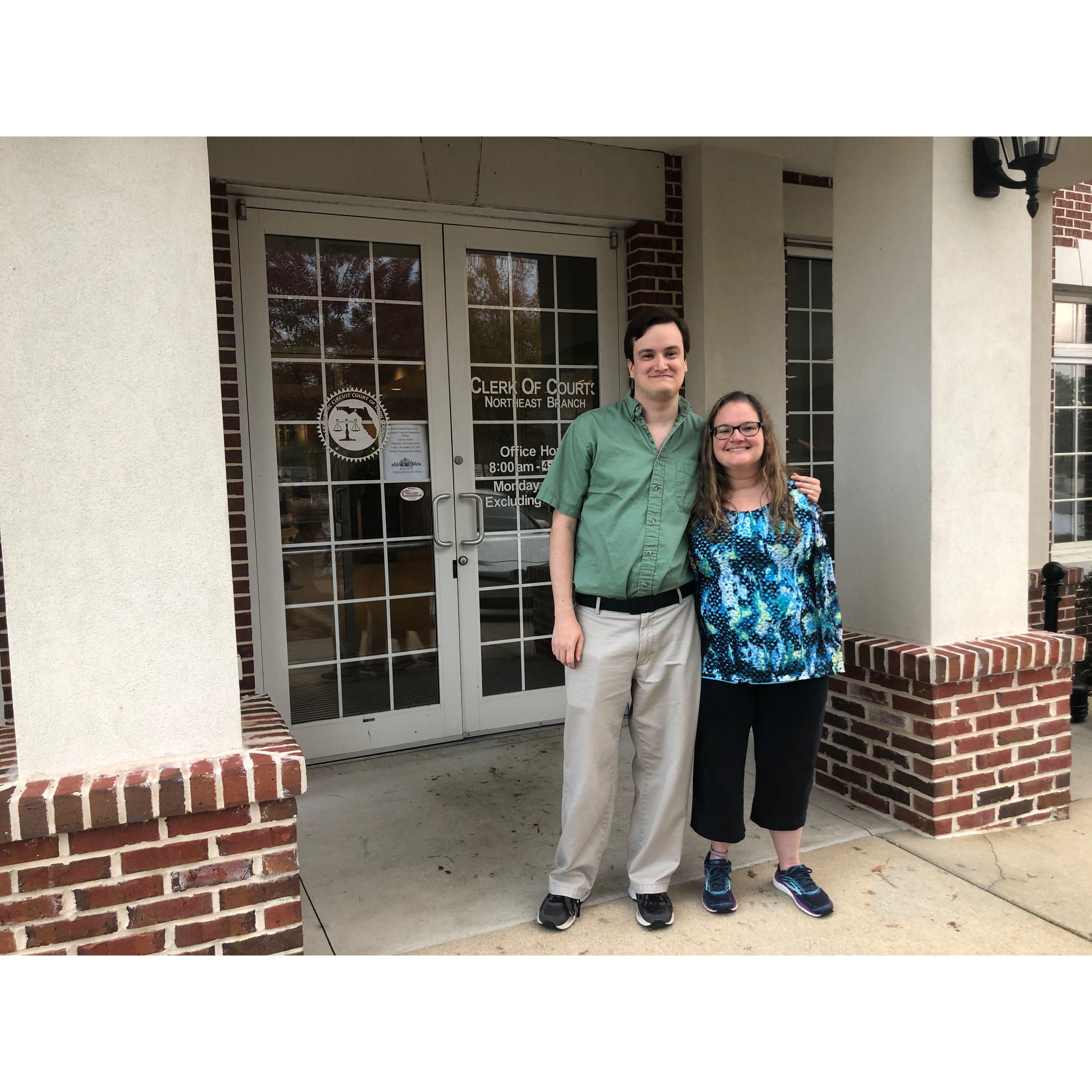 The couple smiling in front of the building for the ‘Clerk of Court’.