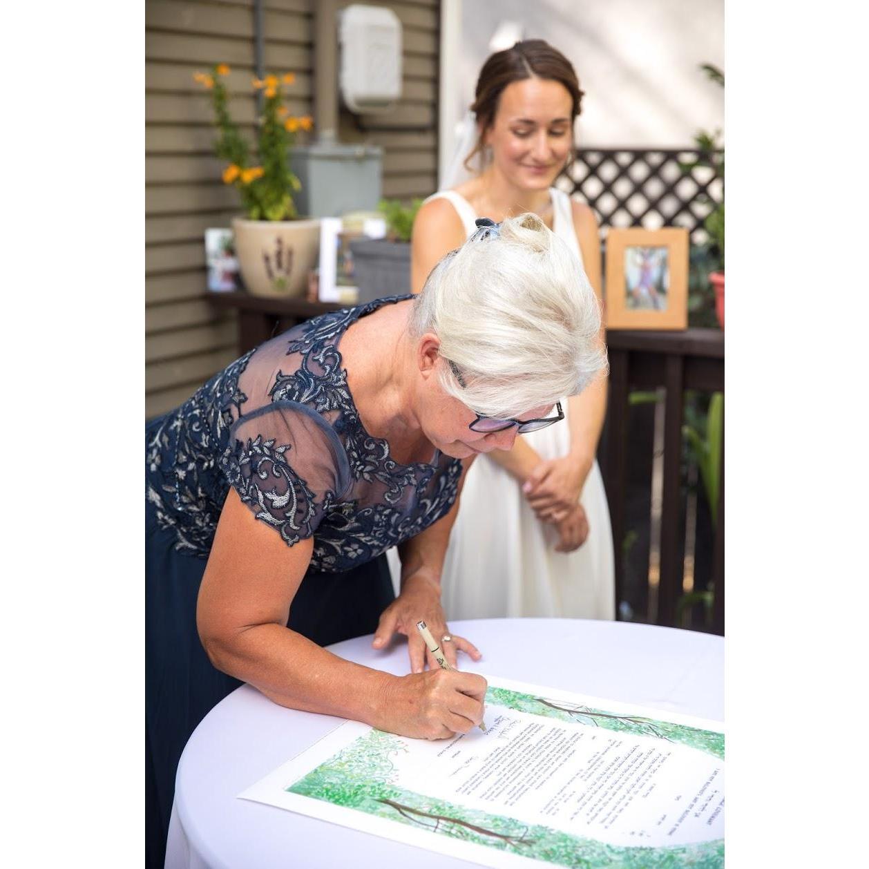 Rachel and her mother, Betsy, signing the Ketubah