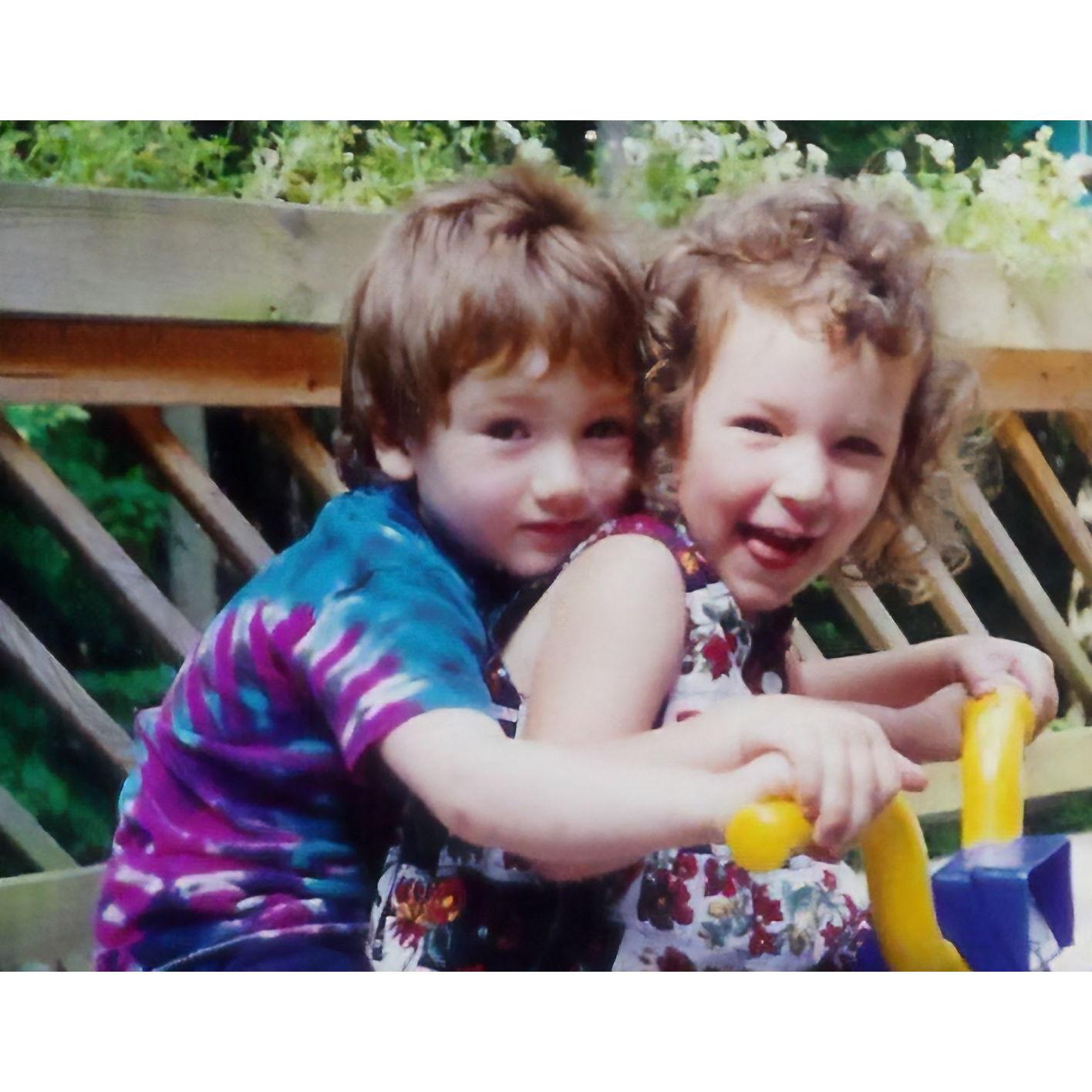 Riding a tricycle together as children.
