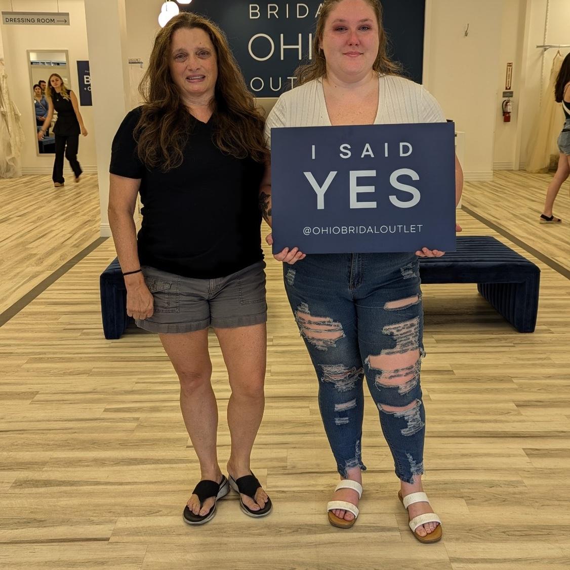 Kirs, chris, and two others went wedding dress looking. She was not planning on getting a dress that day but absolutely loved one of them. When she wasn't looking, Chris surprised her by buying it!