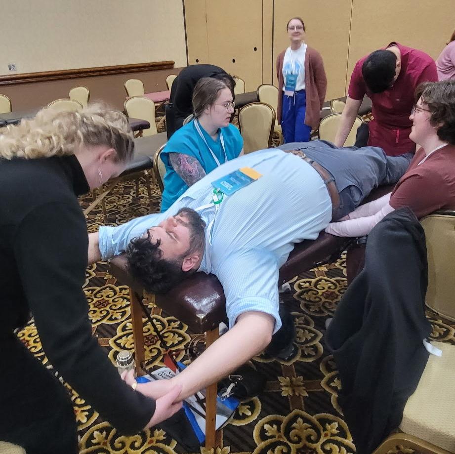 Sam getting treated with osteopathic manipulation by 4 KYCOM fellows