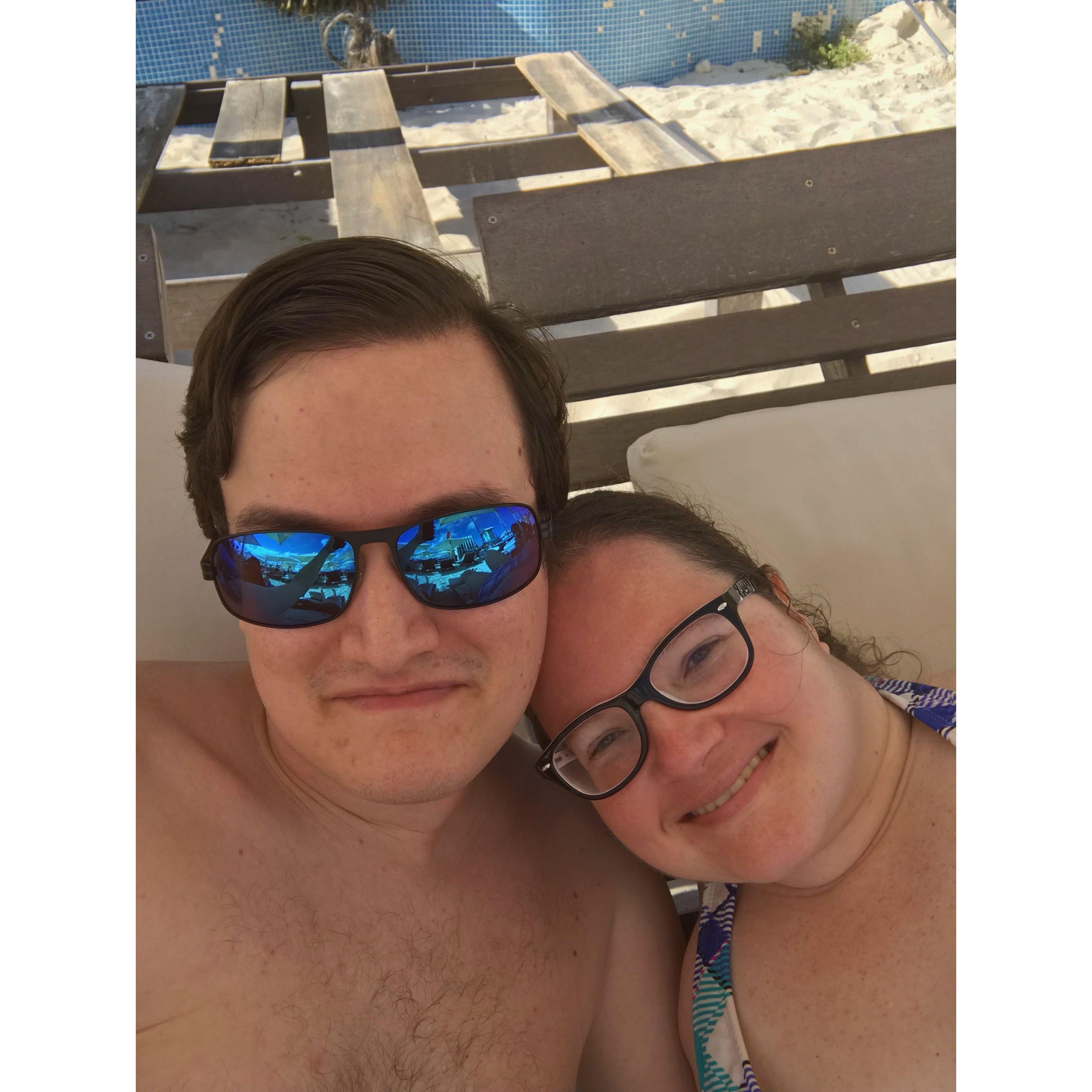 The couple sitting on the beach in Playa del Carmen, Mexico, in reclining lounge chairs under a cabana.