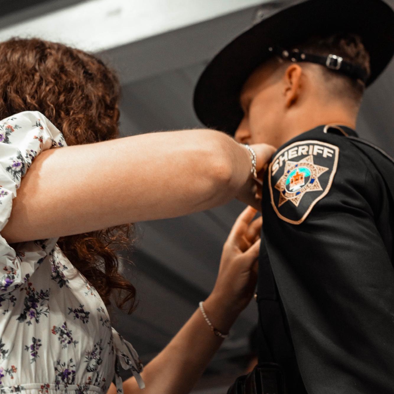 Megan pinning Alex at his police academy graduation