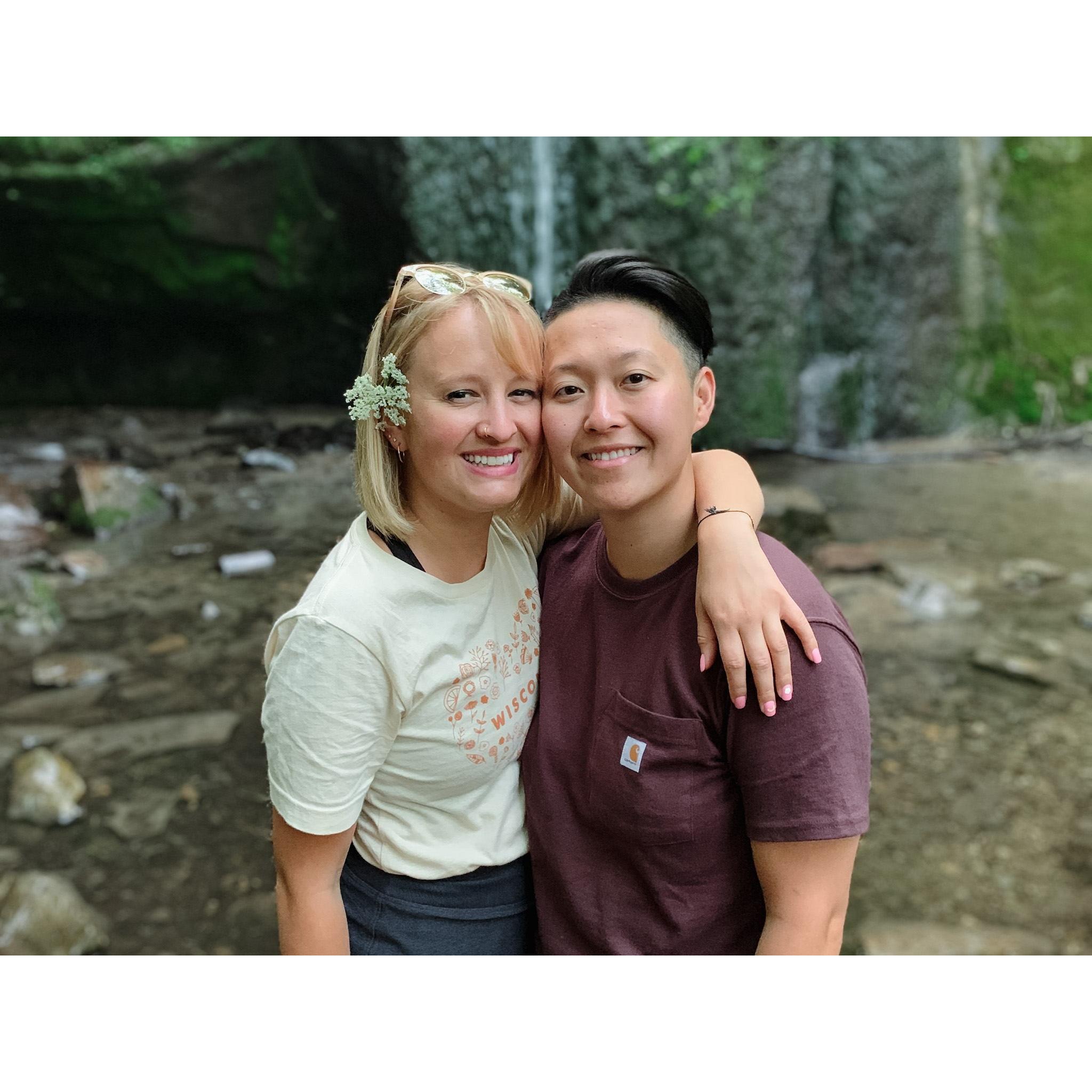 Our first camping trip together in August 2019 at Governor Dodge State Park! Picture description: Ashley and Anhthu are side-hugging in front of a small waterfall.