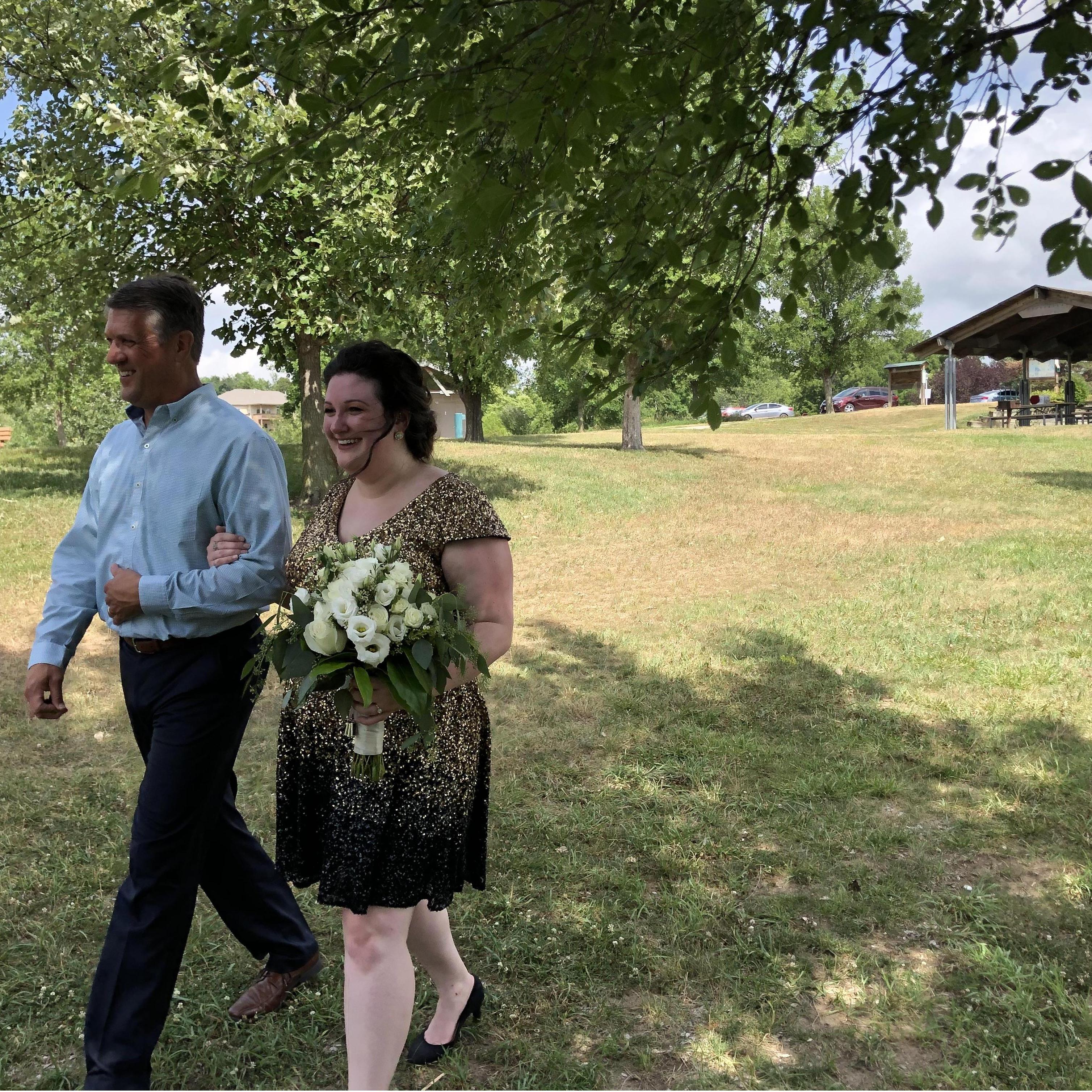 Steve walking Julia down the grassy aisle.