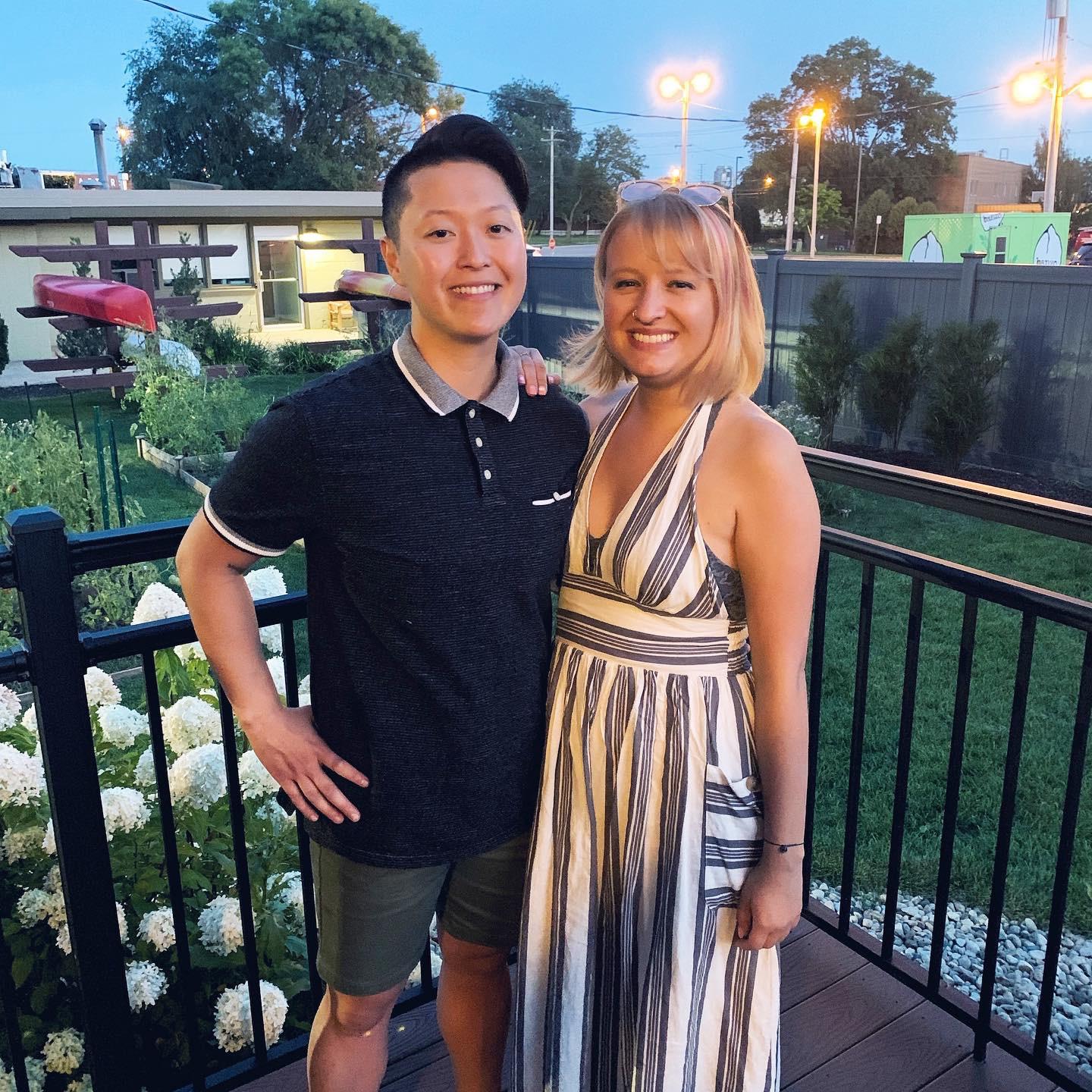 Anhthu’s first birthday that we celebrated together! Picture description: Anhthu and Ashley pose next to each other on a porch with green grass and a white flower bush in the background.