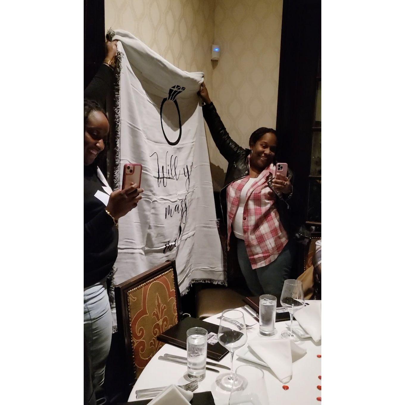 The "Will you marry me" sign held by Chiquita's cousins.