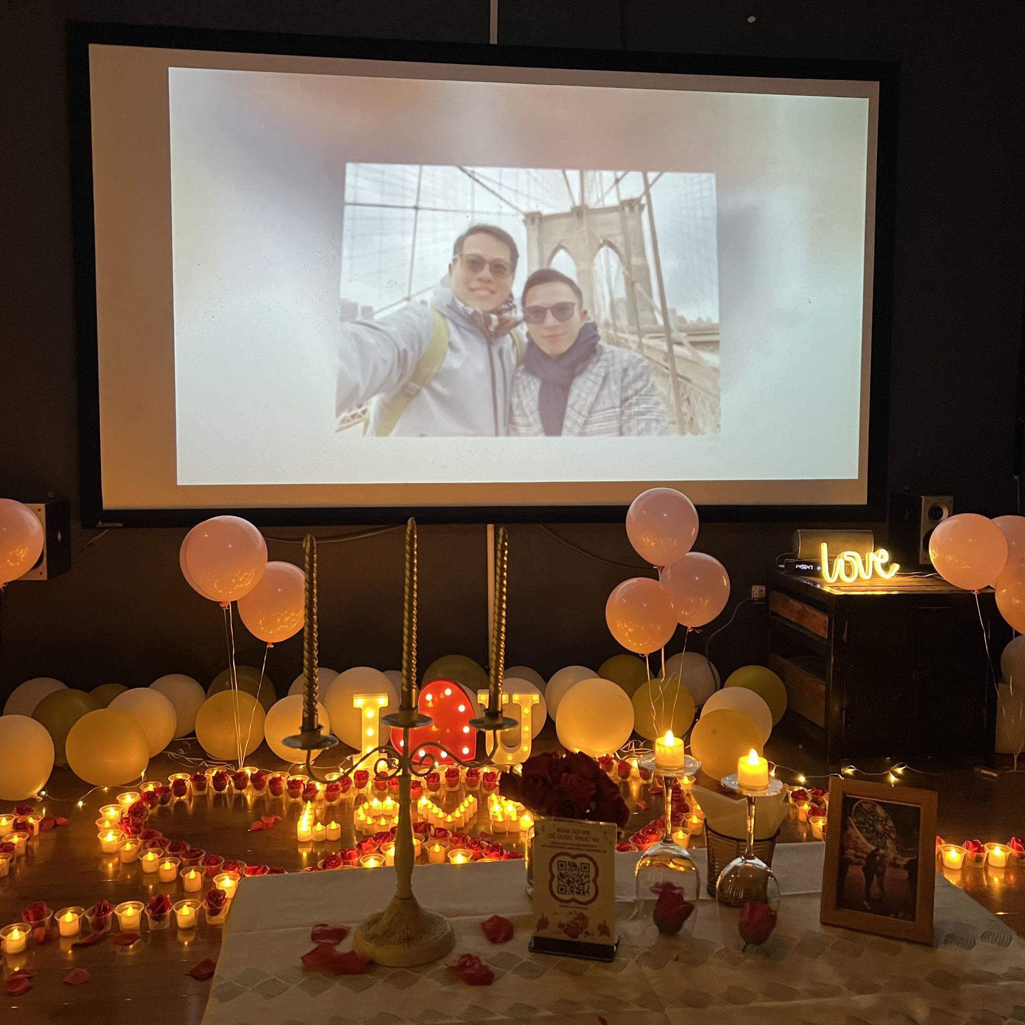 (18) A barista led Tho into a private room decorated with balloons, rose petals, and tea lights illuminating a backdrop where a slideshow of their time together was running alongside romantic tunes.