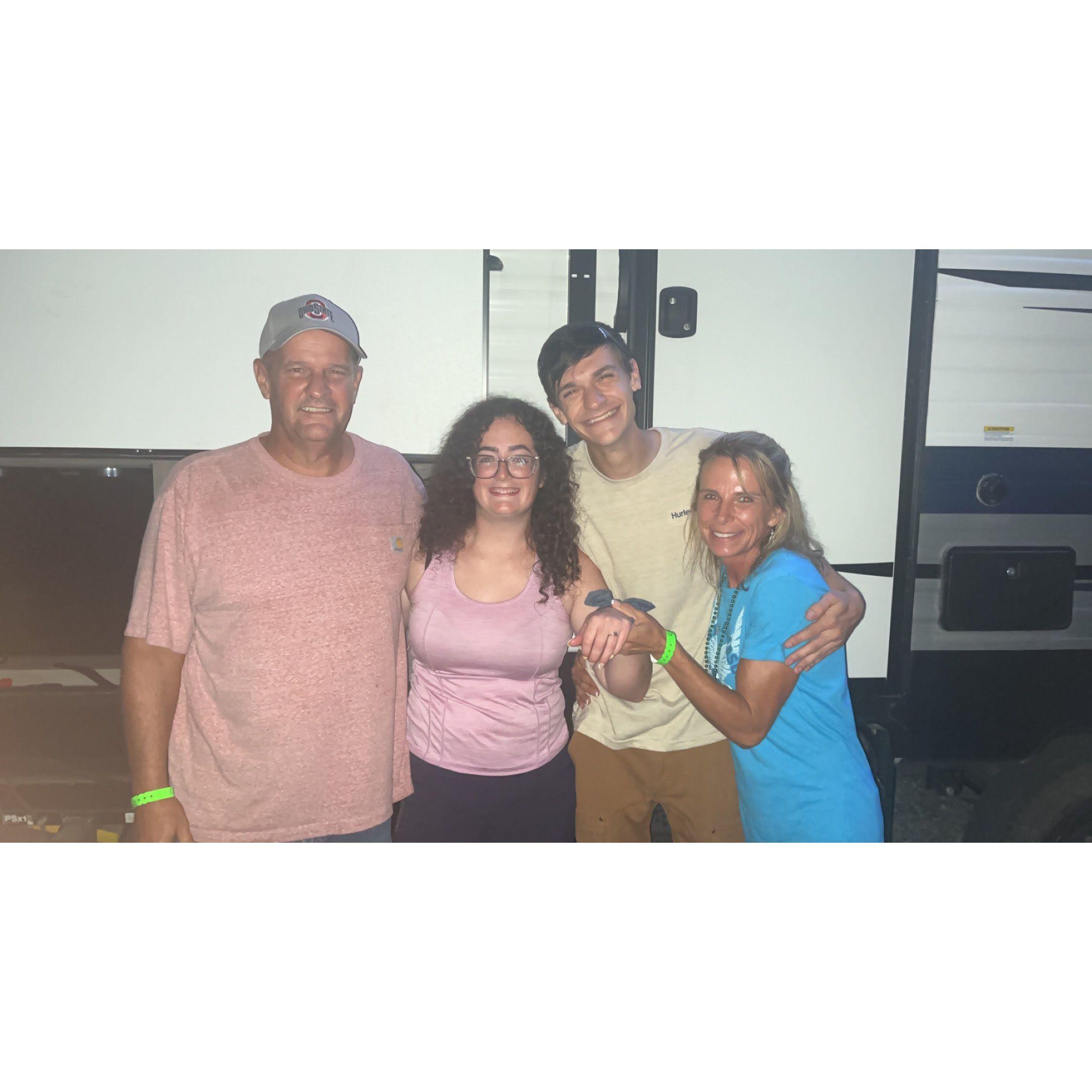 Adam and Bailey standing with his dad Ed and stepmom Stacy right where Adam proposed.