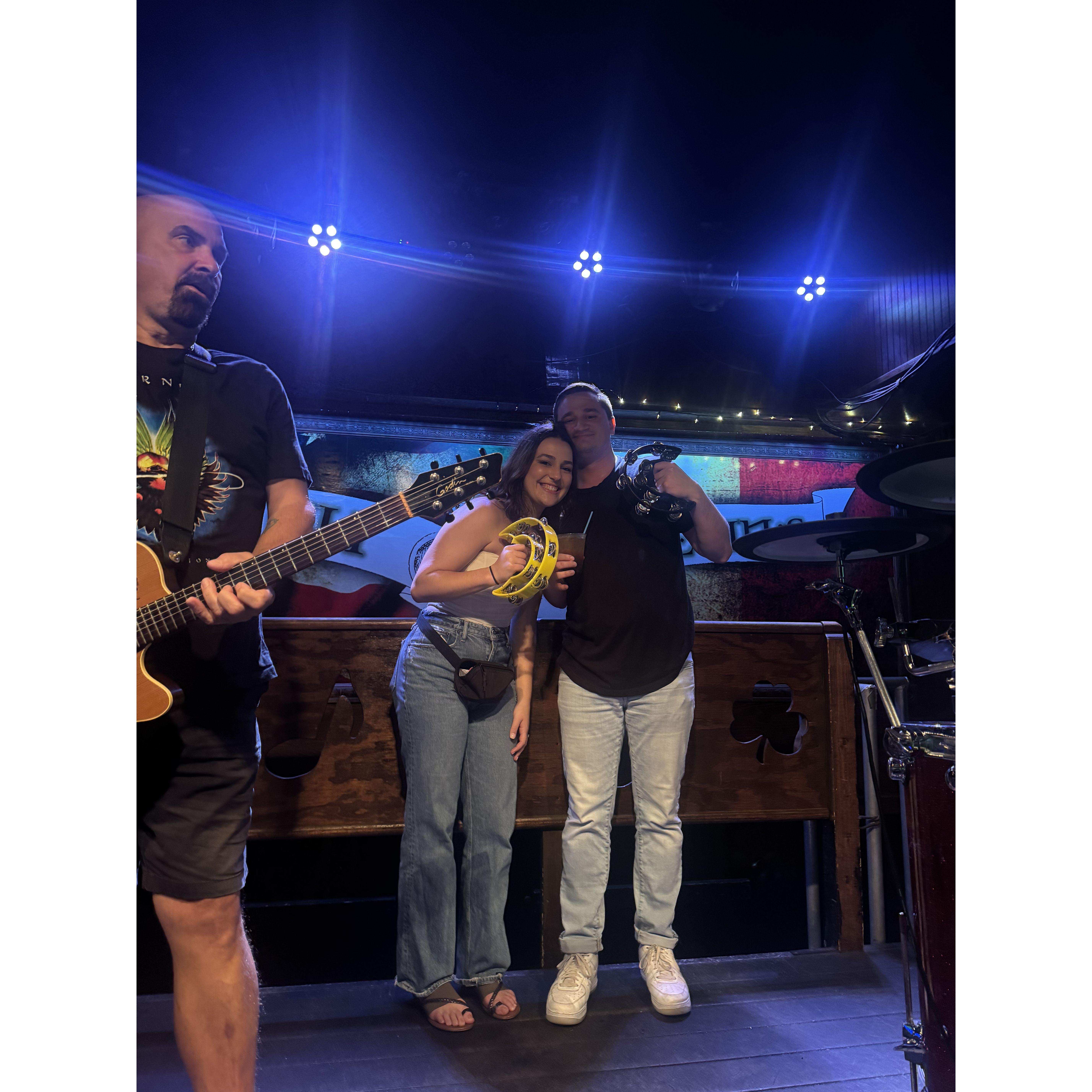 Liam and Maddie on stage performing Liam's favorite song on tambourine in Key West as Maddie's engagement surprise to him