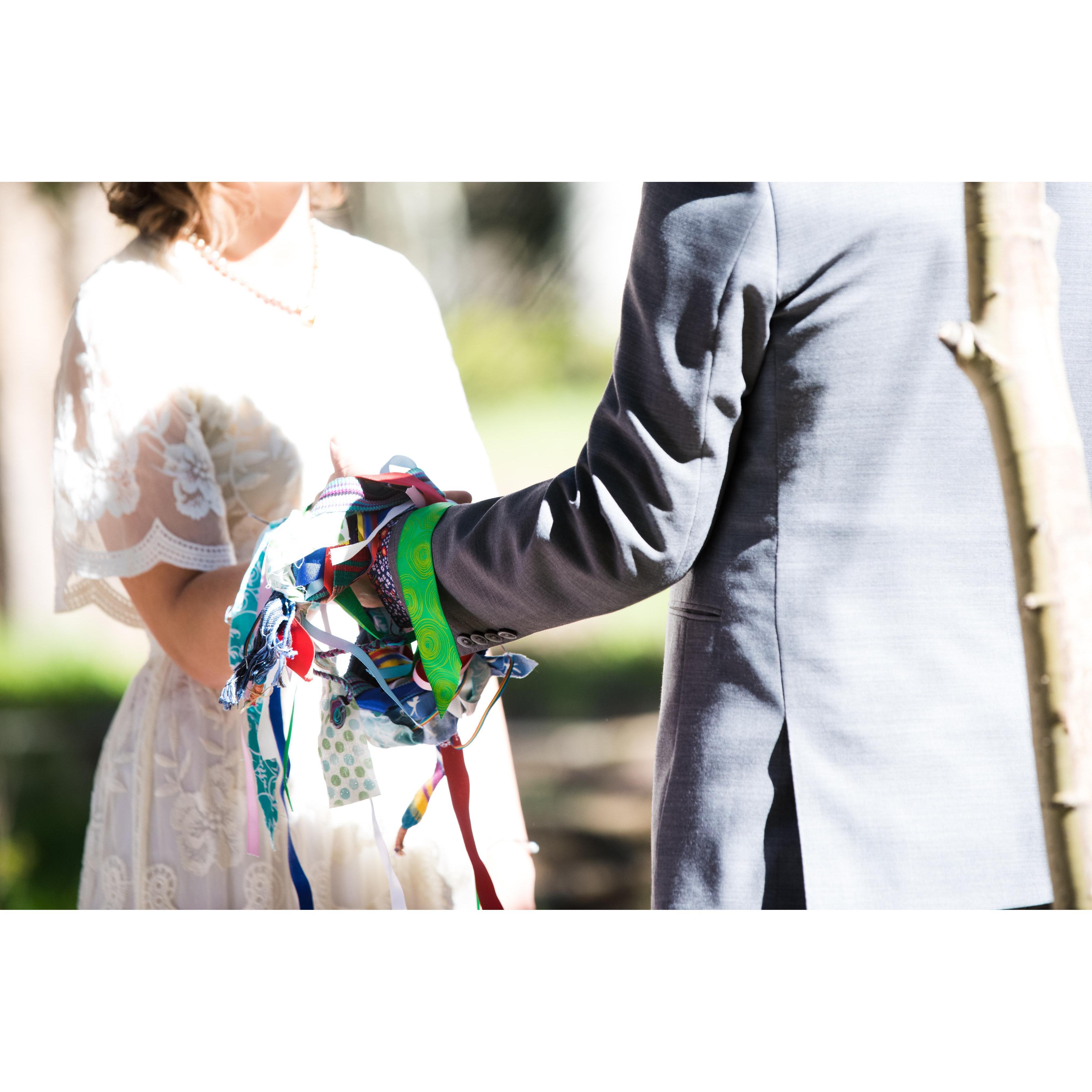 A stole of ribbons brought by family members draped over our hands.