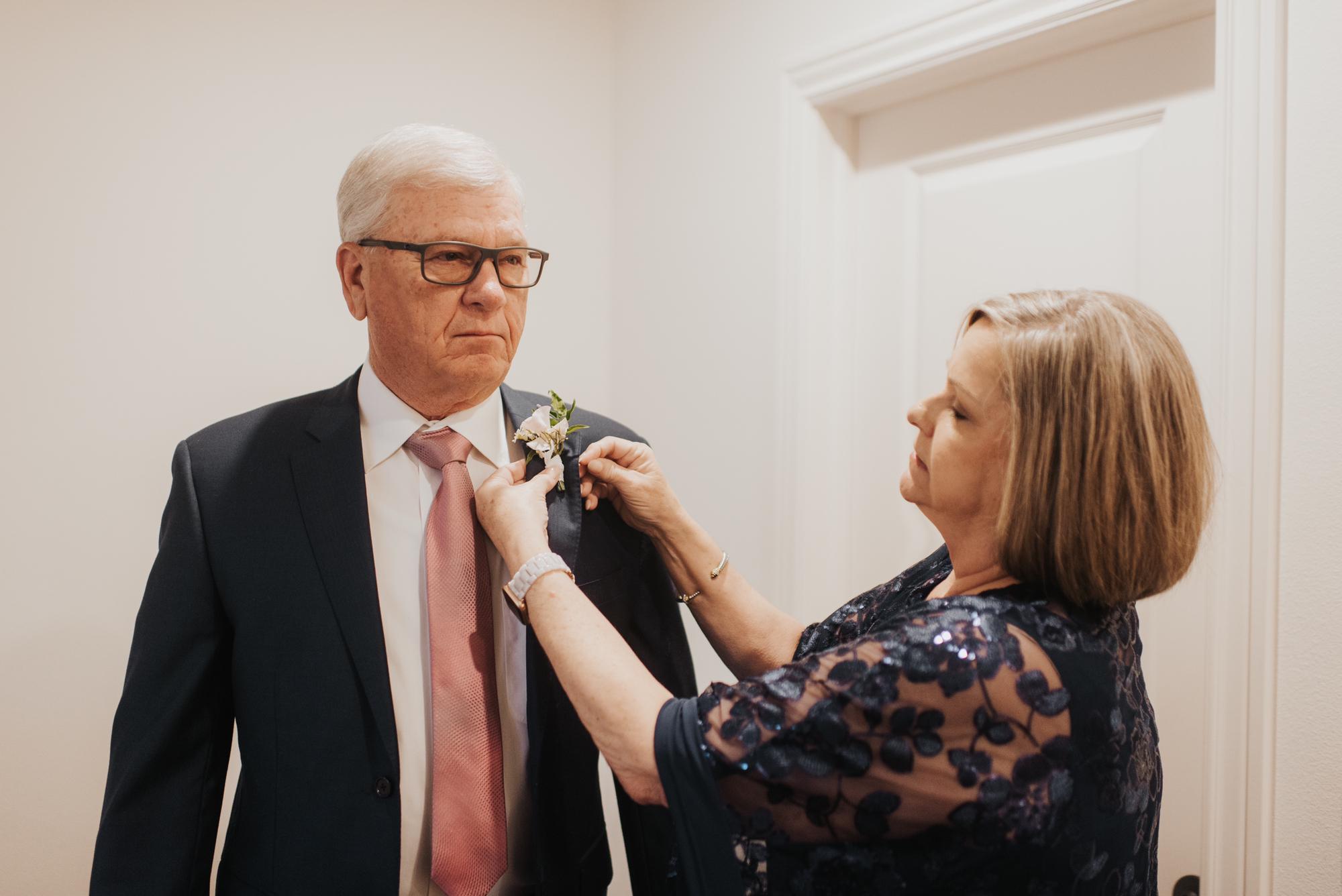 Mother of the bride, Jana, helping pin the boutonnière on the father of the bride, Wendell