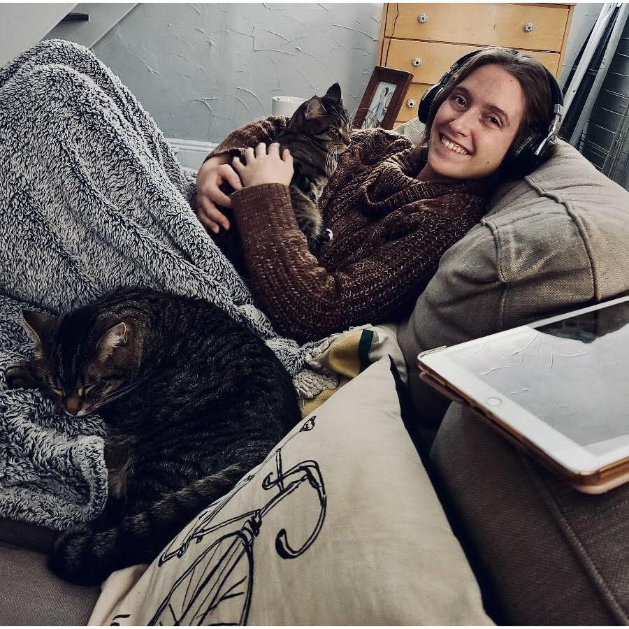 Happy because she has two cats, a blanket, and her headphones to block out the music blasting from the apartment next door.