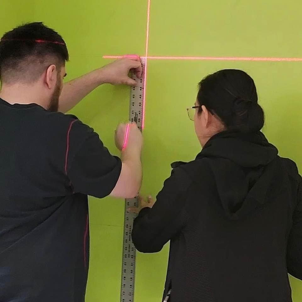 A photo of my fiance helping measure out my designs on the 18 ft and 25 ft high wall.