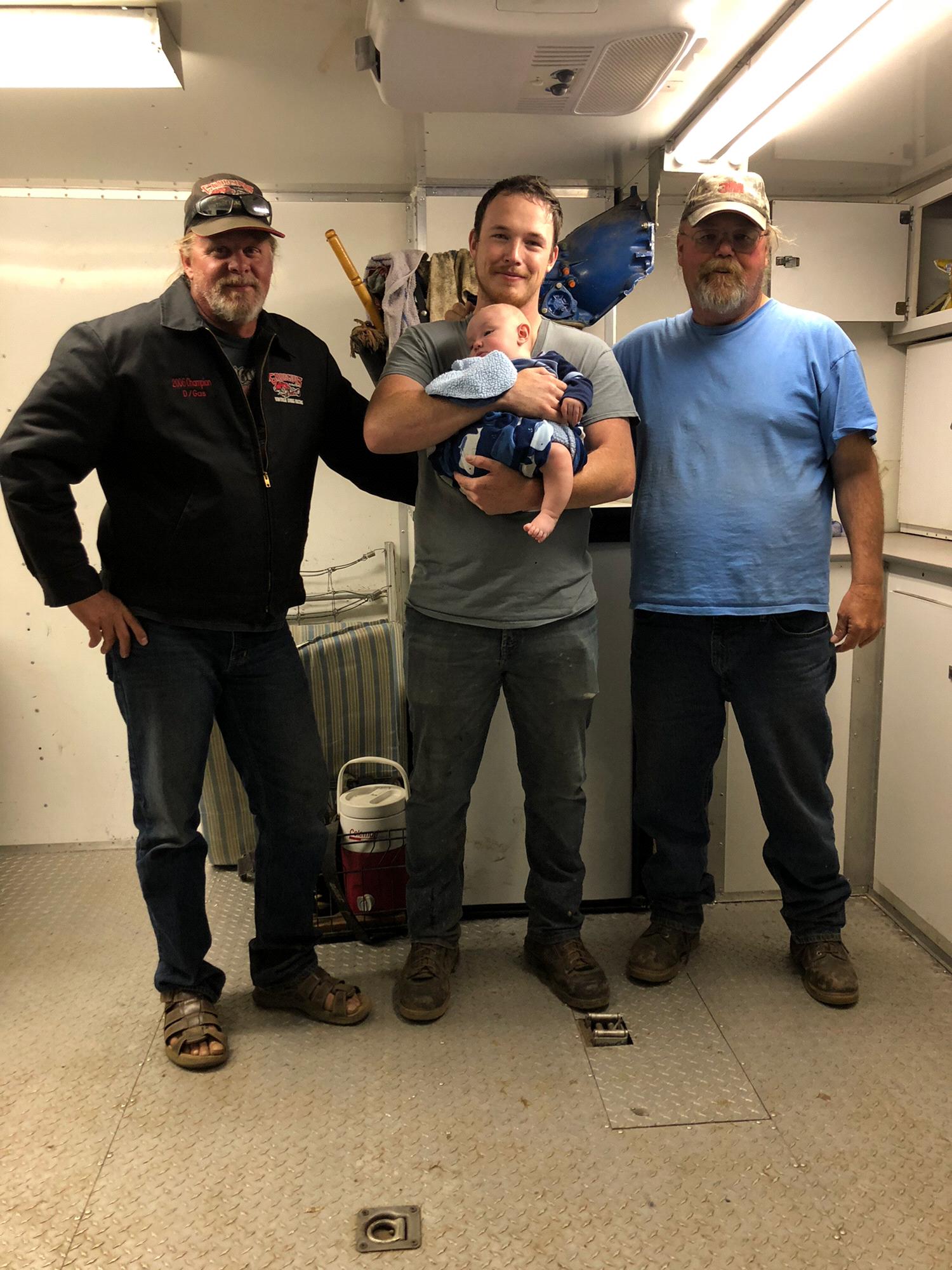 Matthew holding Nathan, standing next to his father Robert and family friend Todd.