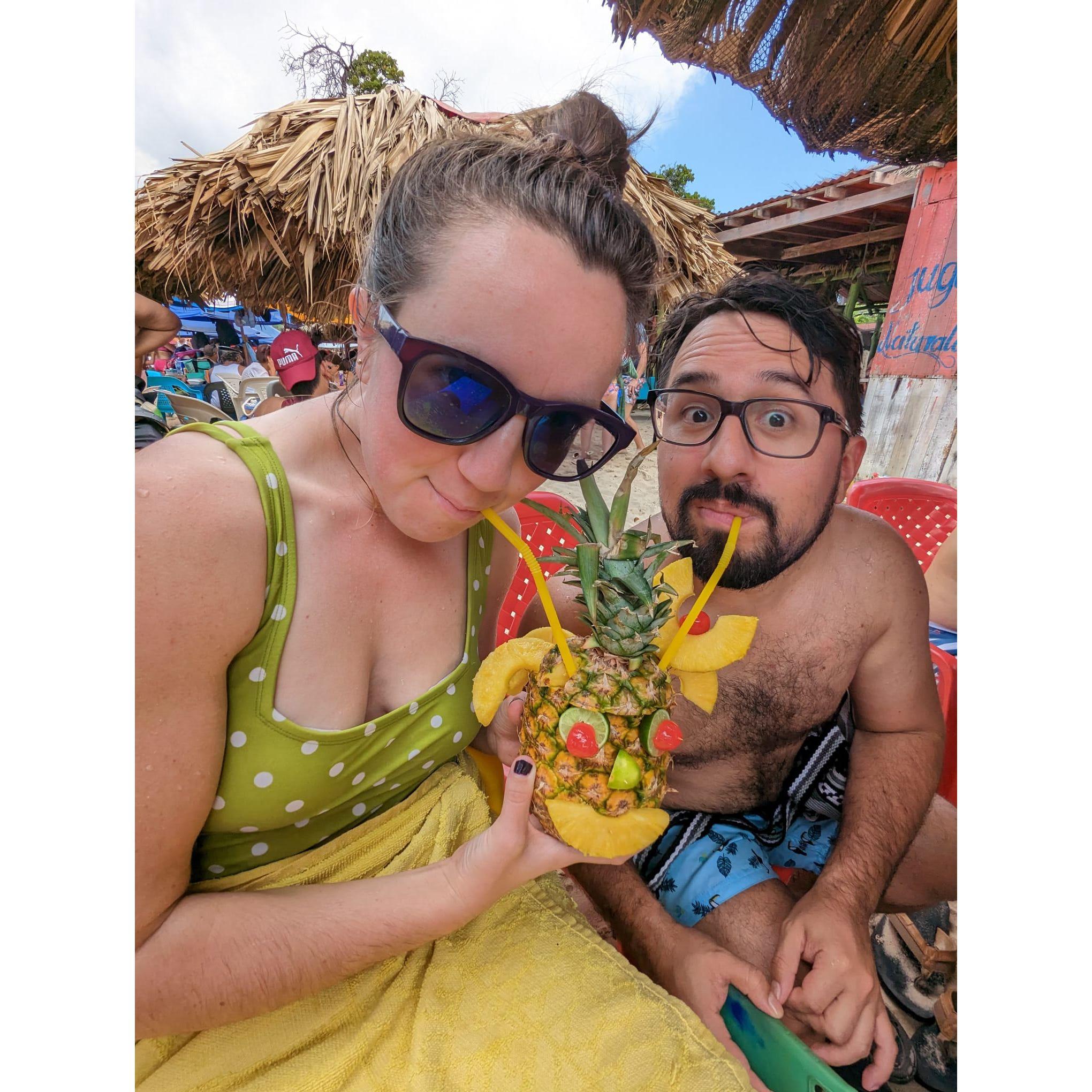 Felipe and Sarah love fruity adult beverages! Here's us enjoying a piña colada on the beach in Colombia.