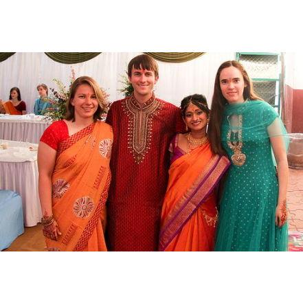 A variety of styles including orange women's Saree, red men's Kurta and turquoise indo-western dress with Dupatta (scarf)