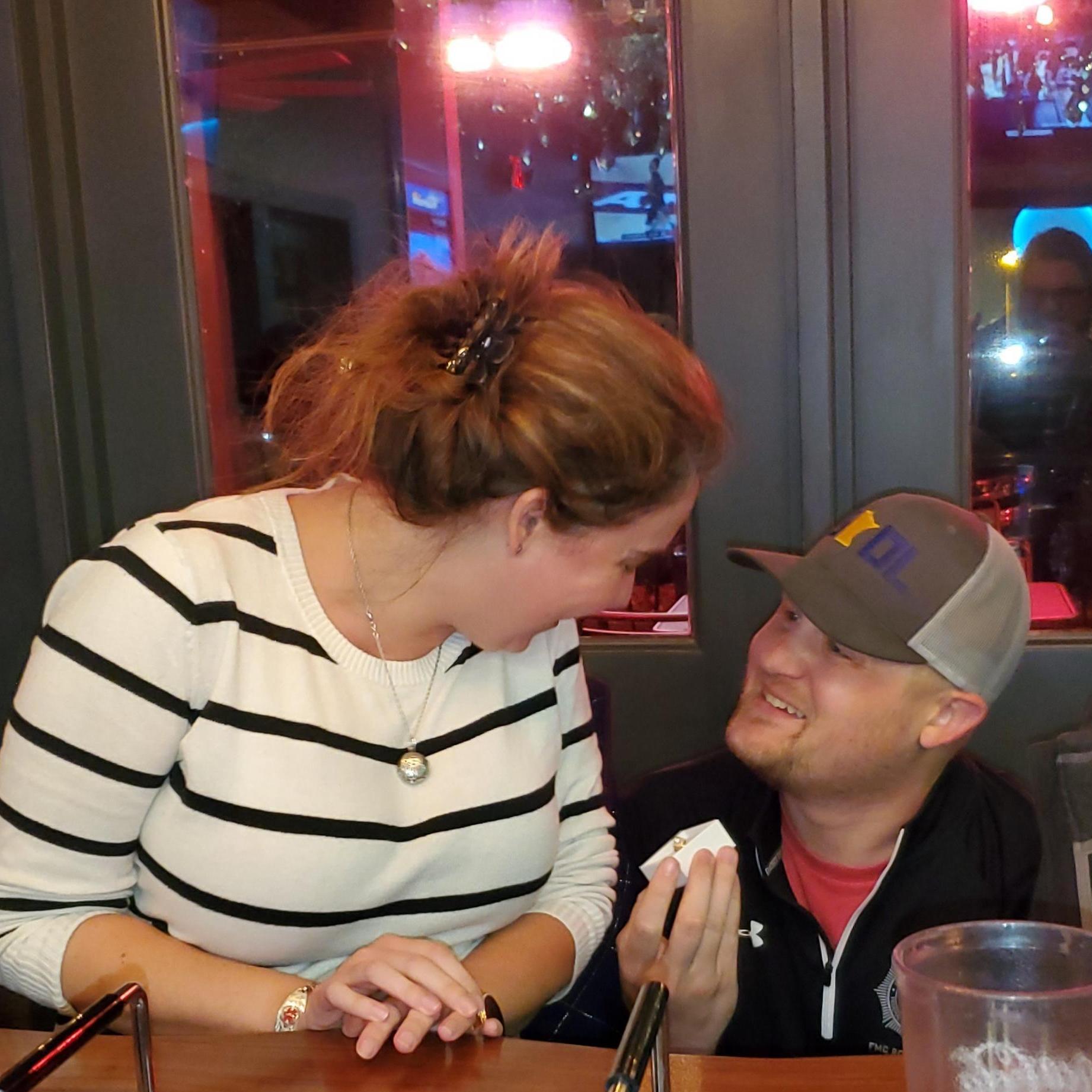 He popped the question at trivia night! Jules had no idea it was coming (or she might have fixed her hair.)