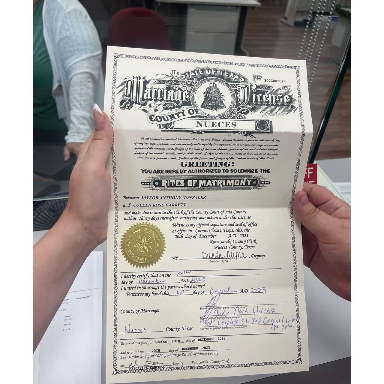 Coleen and Jaykob holding their marriage license together, December 20th, 2023