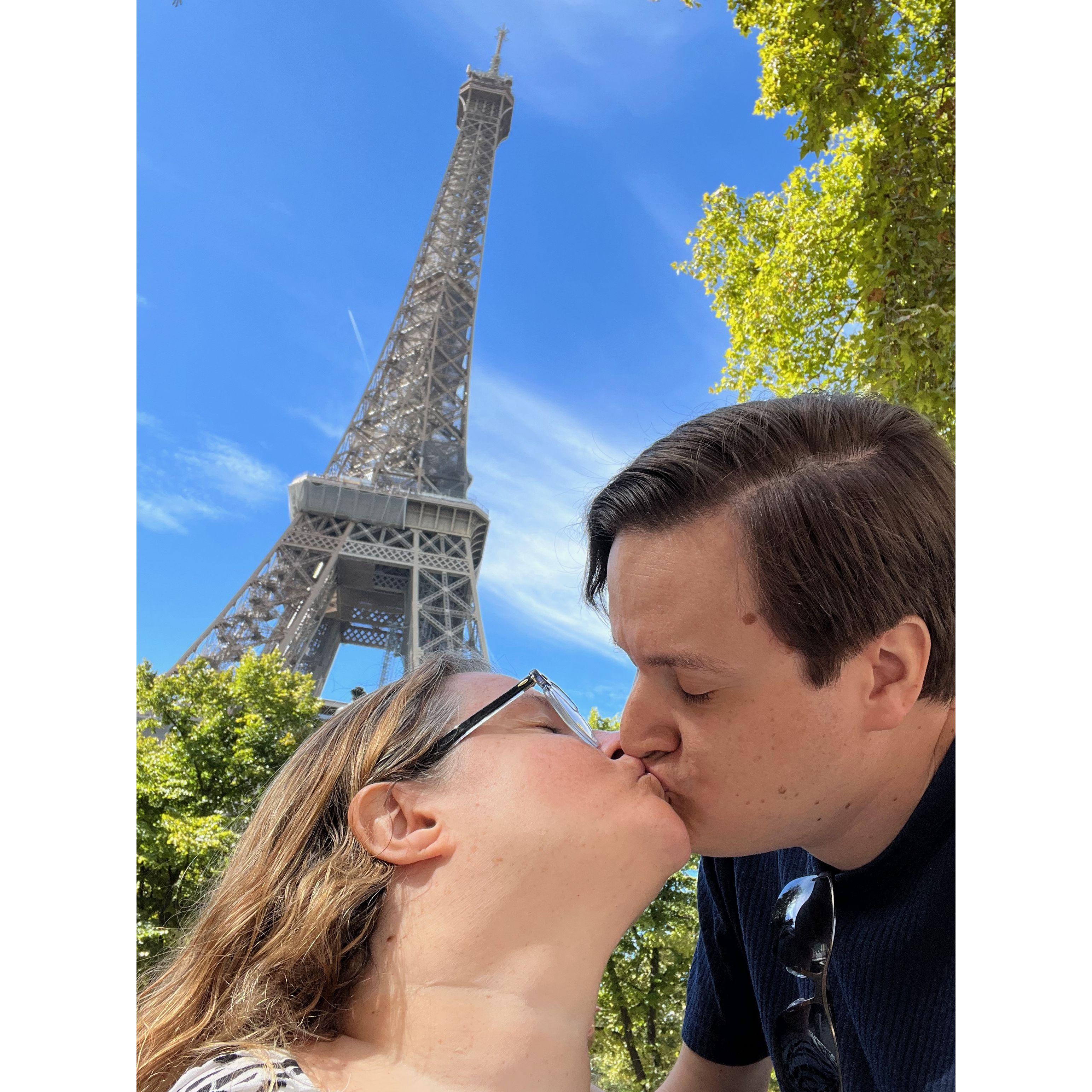 The couple kiss with the Eiffel Tower behind them.
