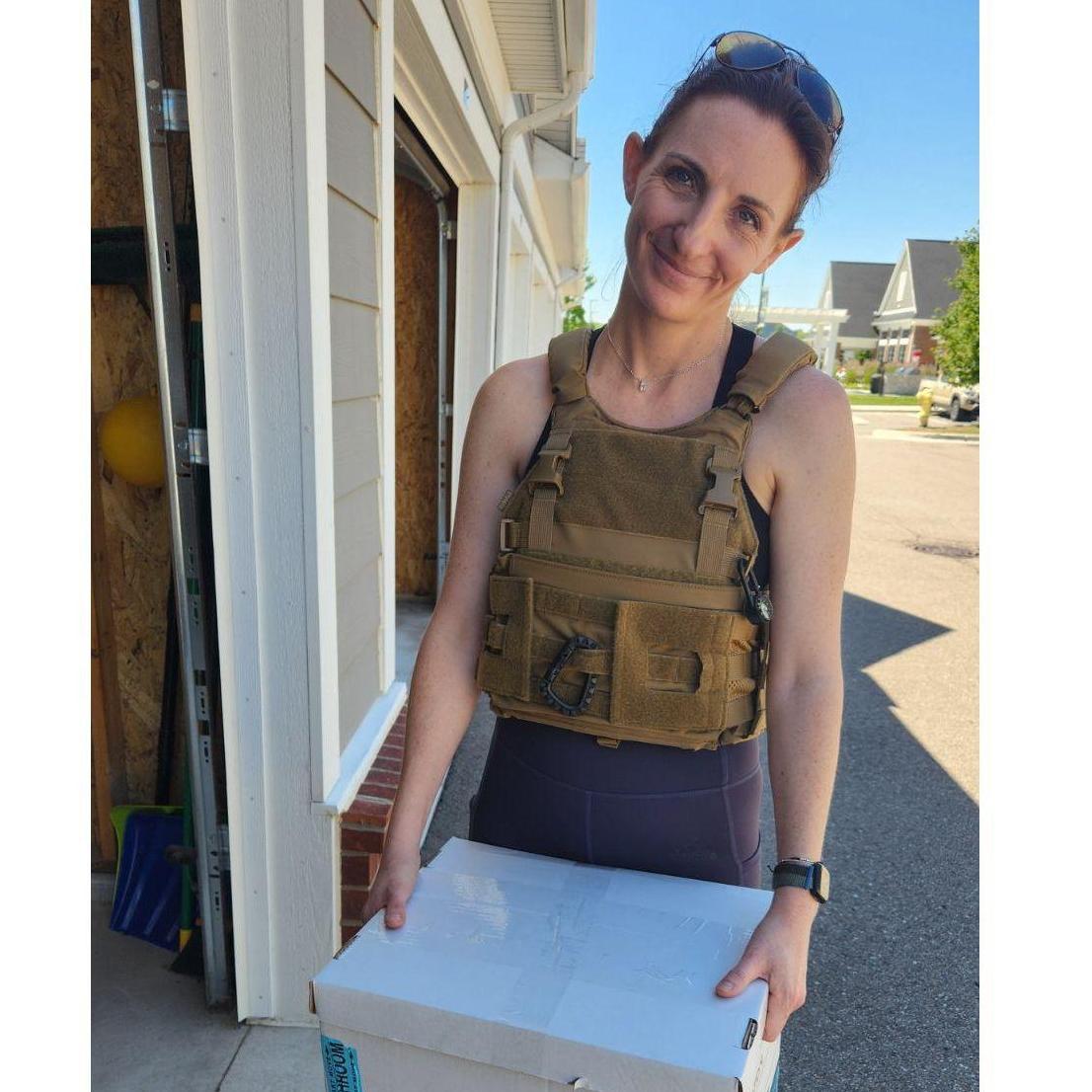 Ändrea helping Roy move into his apartment, being silly wearing armored vest. May 2024