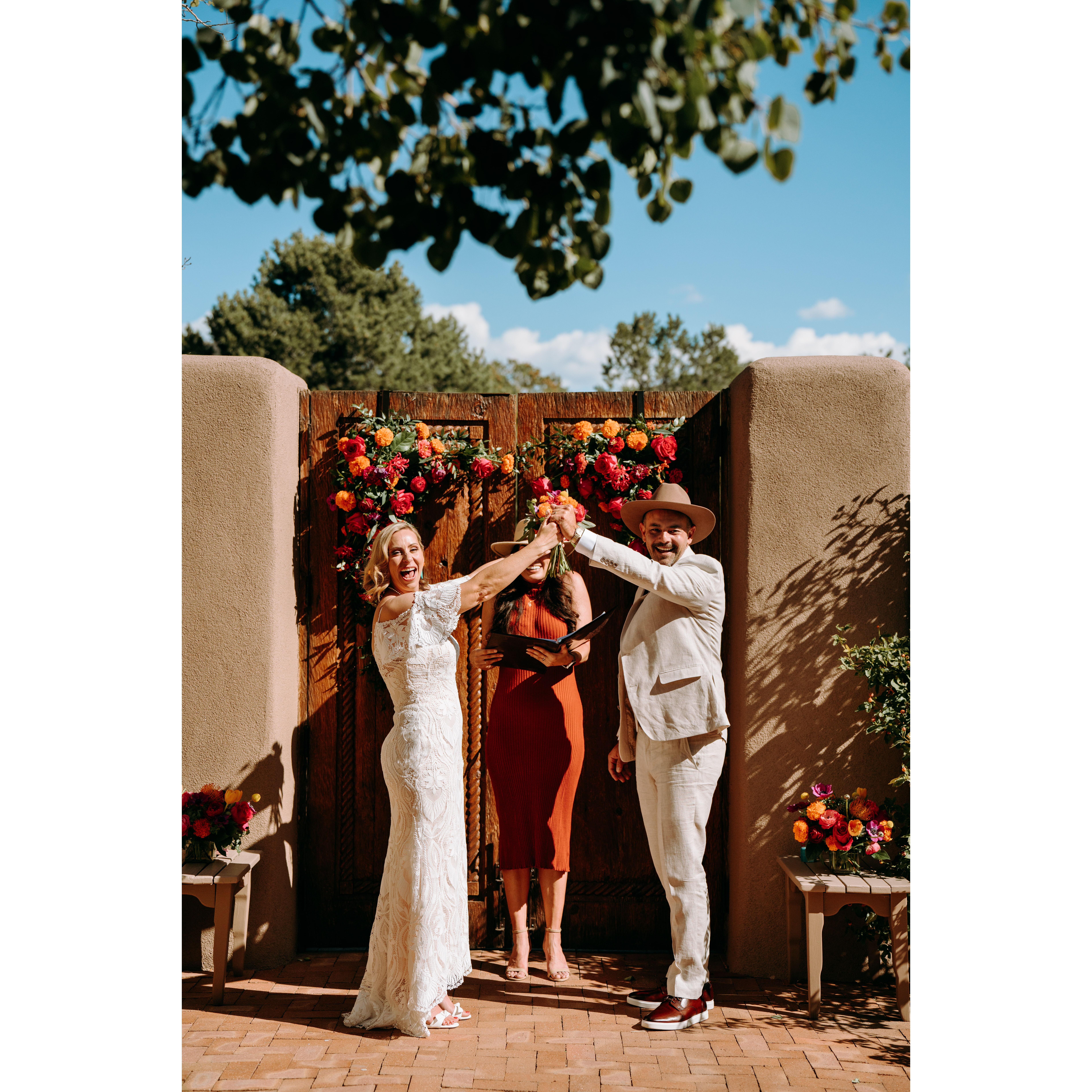 Vow ceremony - Jenn and Shae lift their arms in celebration as Marie announces them husband and wife