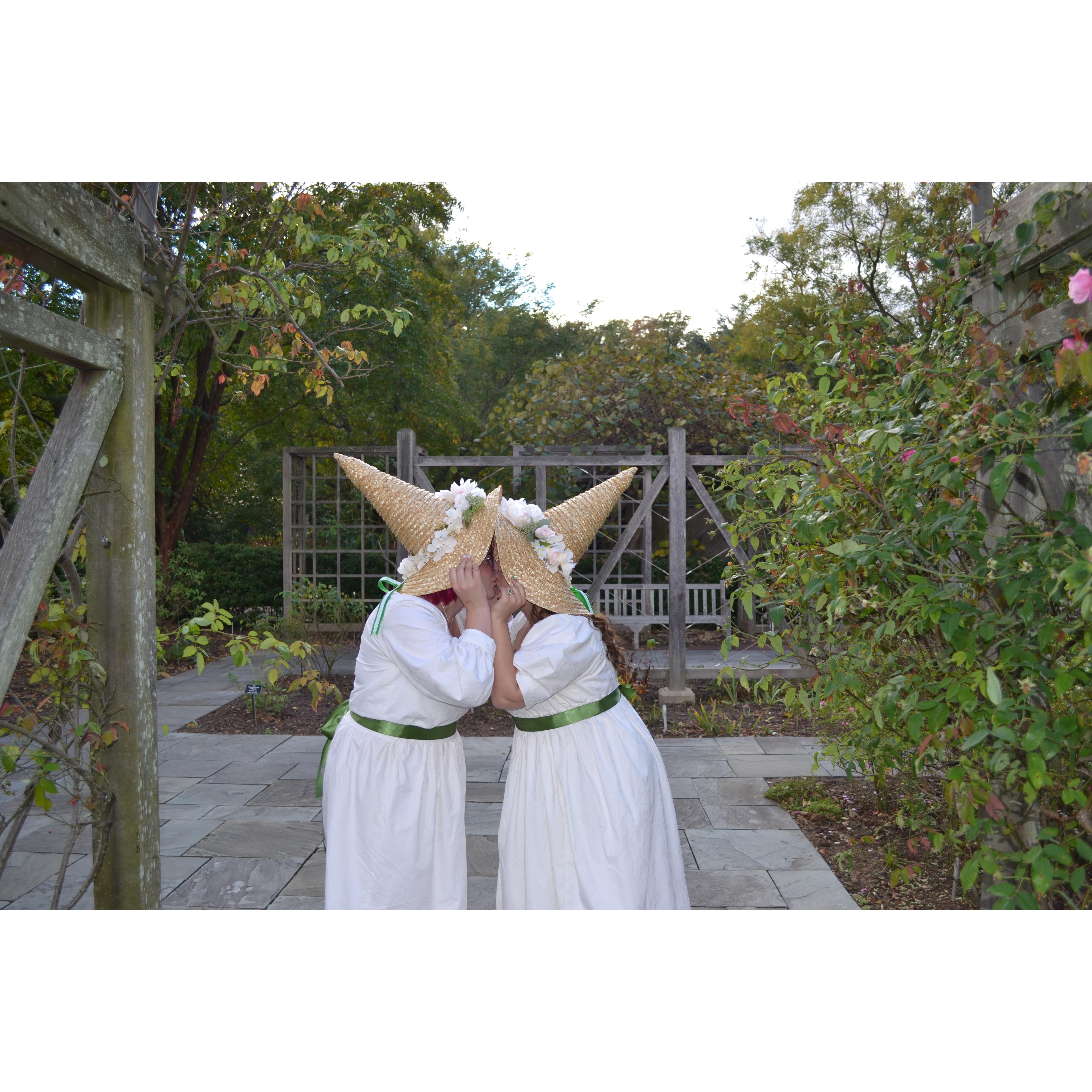 The brides trying to snag a kiss from underneath those hats!