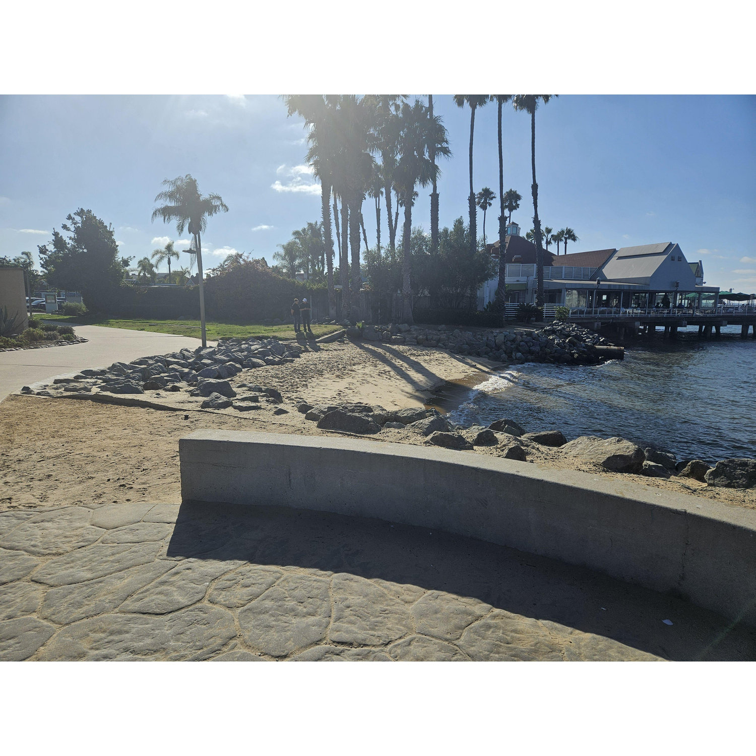 Where our ceremony will be held. Guests have choice to stand on pavement, grass, or sand. As stated in the FAQ, we are happy to provide seating as needed. The ceremony is expected to last 20 minutes.