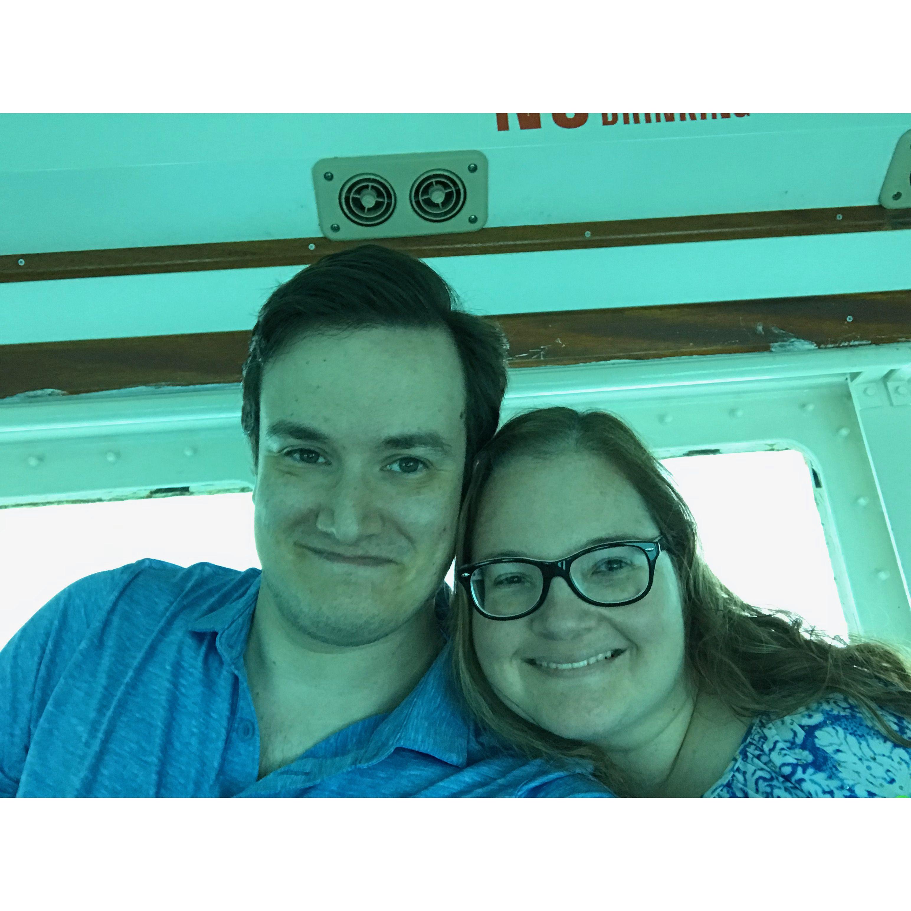 Oliva and Zac smiling while on a submersible boat in the Bahamas. They match clothes, both wearing blue.