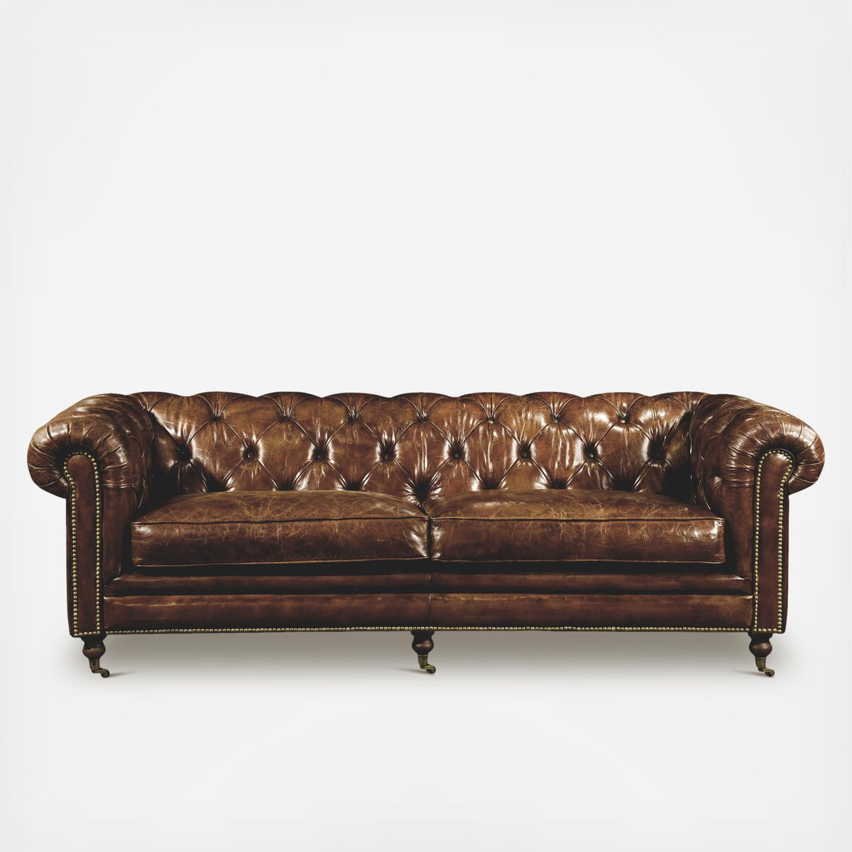 Brown leather Chesterfield sofa with tufted back and arms, brass studs, and wooden legs