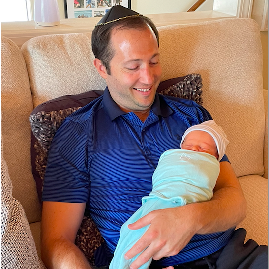 Godfather Corey holds his first nephew Shafer after his bris.