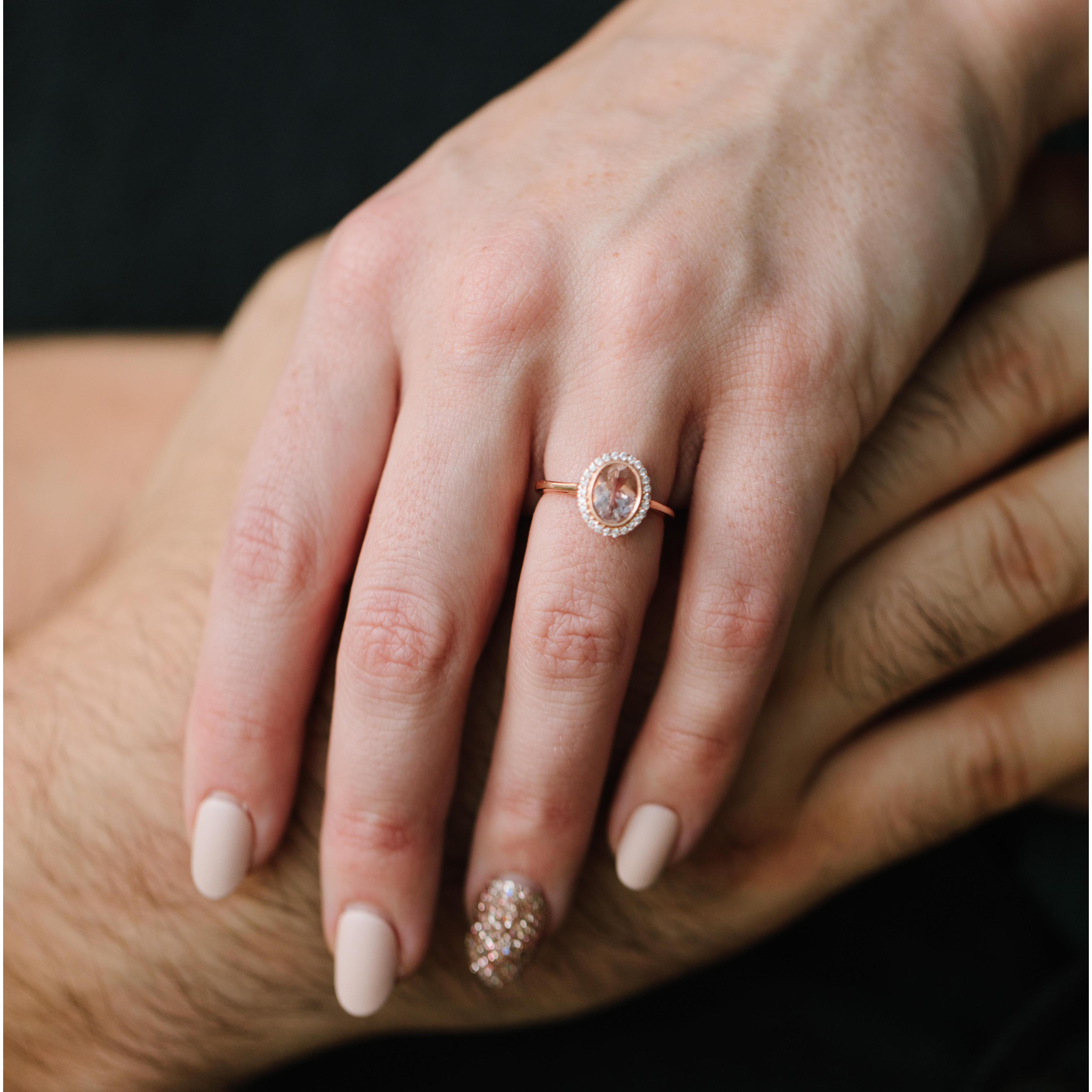 Rose gold metal with a pink morganite center stone and diamond halo. The bevel set oval gives it a vintage feel that Rachel fell in love with instantly.