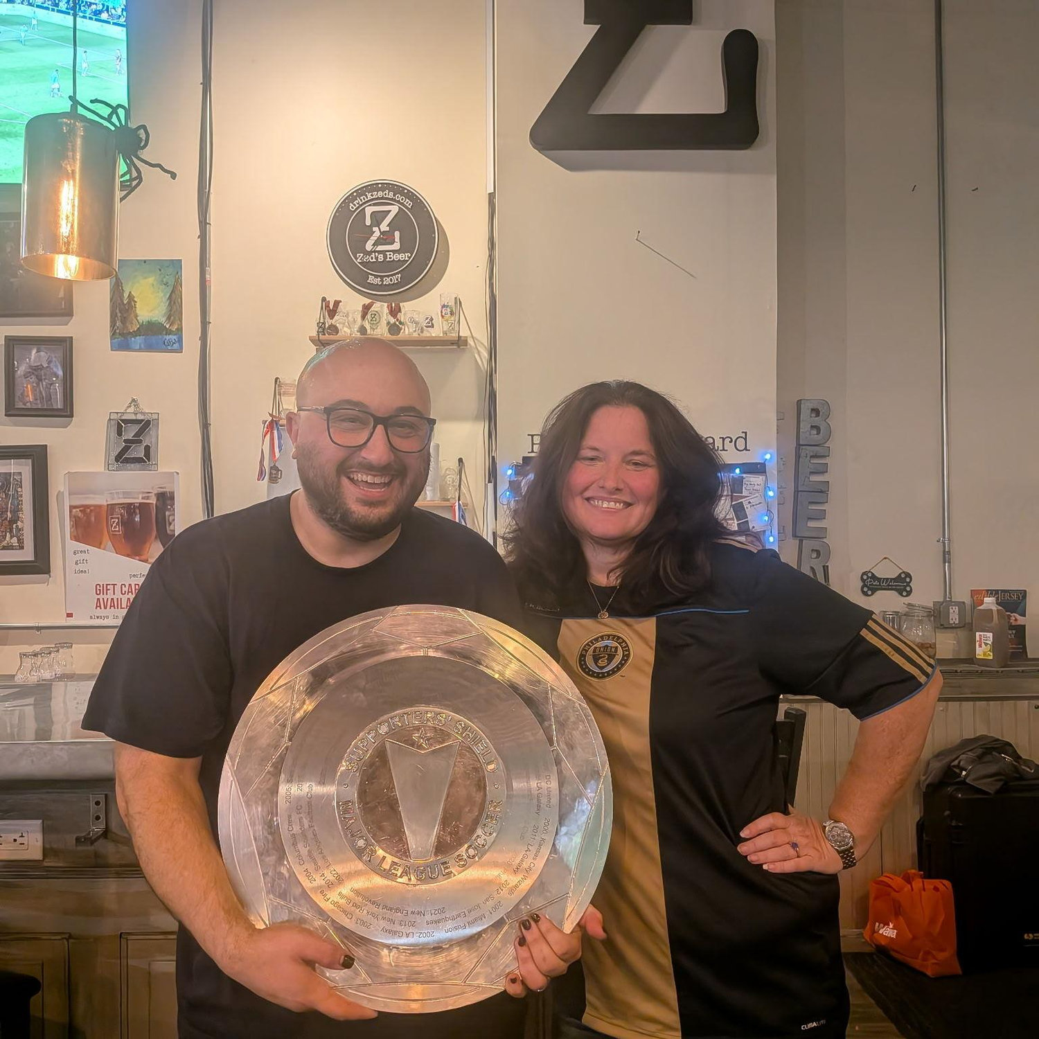 Justin and Amy with the Supporters Shield at Zeds Brewing
