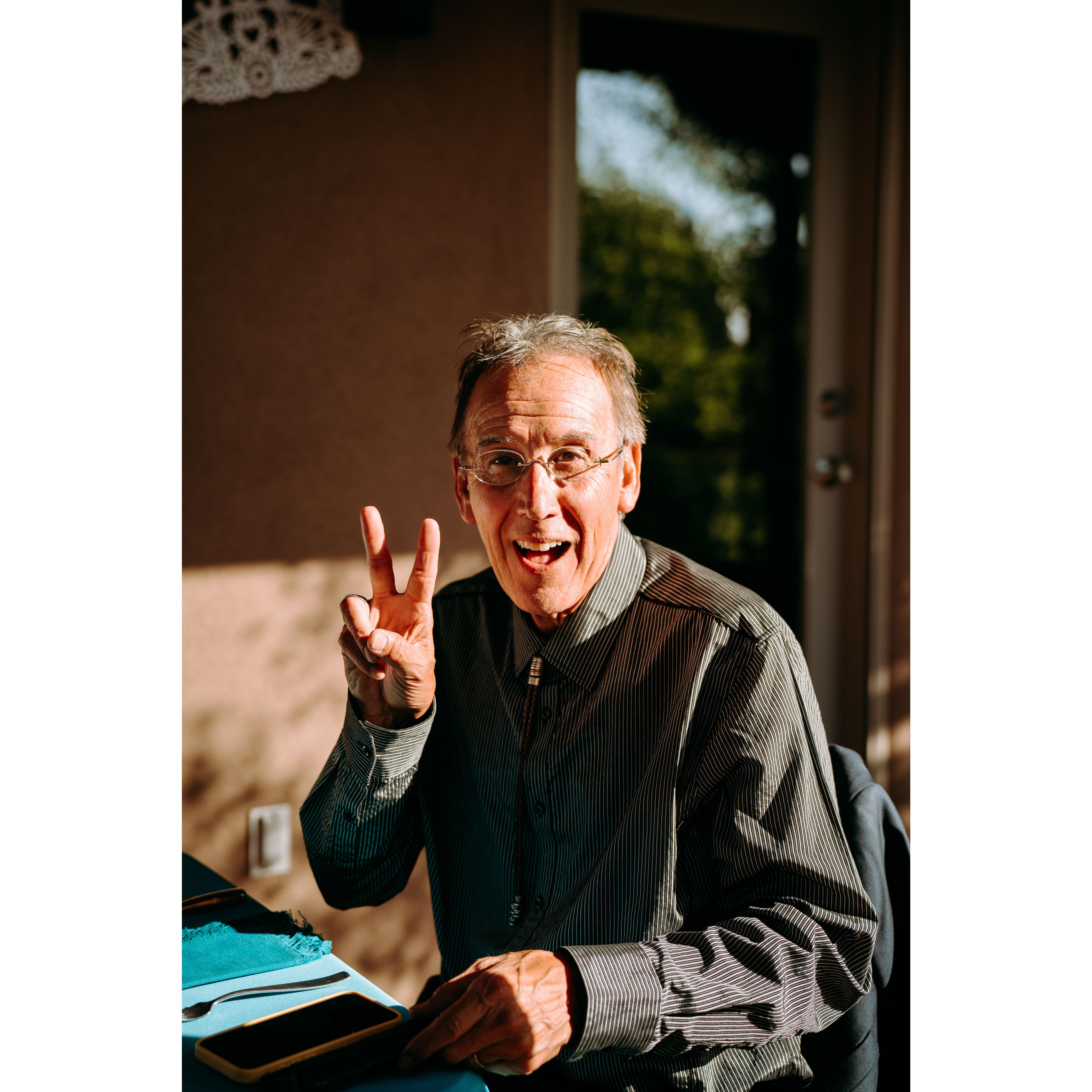 Ric (Shae's Dad) gives a peace sign and a smile at reception dinner