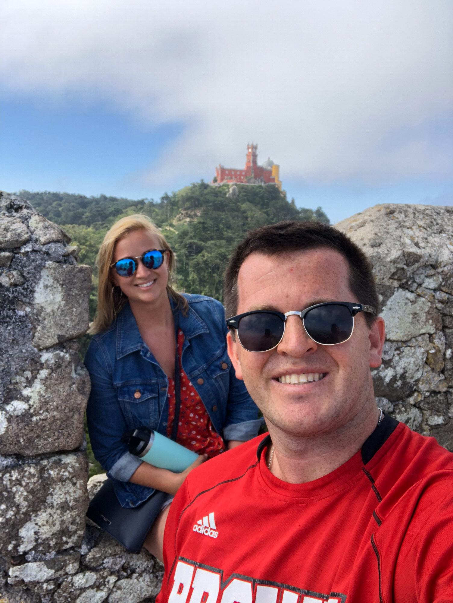 Sintra, Portugal. Sitting on top of Castelo dos Mouros with the view of Palacio Nacional da Pena in the background