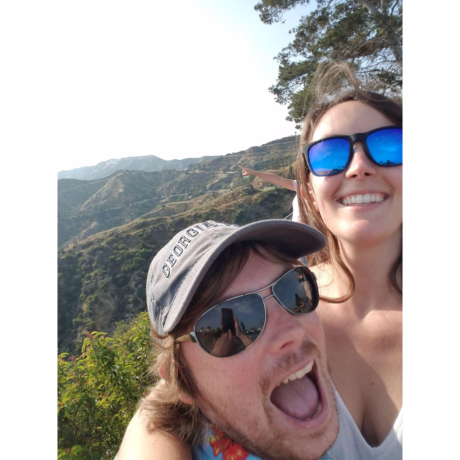 The Hollywood sign obscured by LA smog, but the guy behind Alex is conveniently pointing it out.