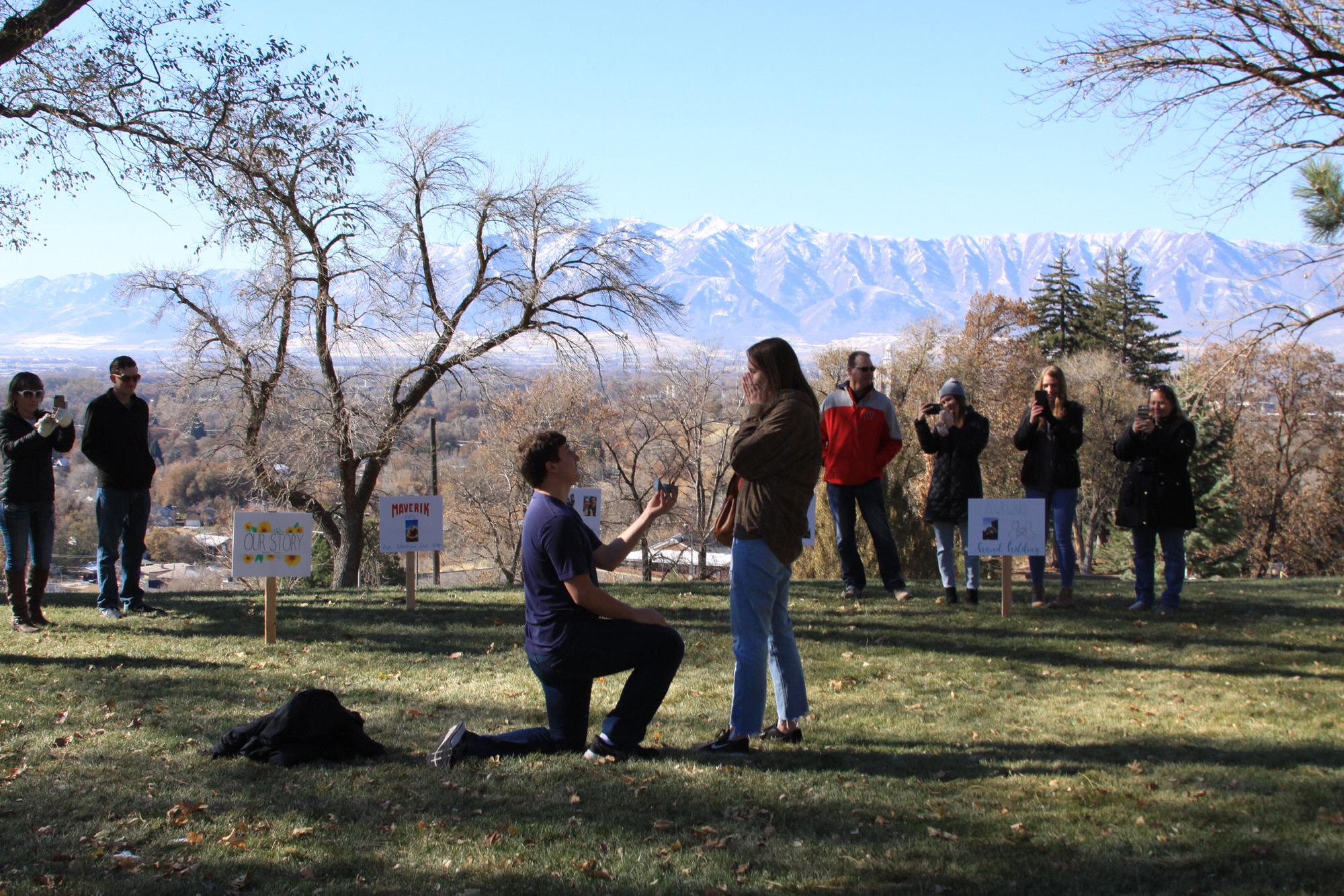 Cade proposing at our "spot" on campus with both our families there. With the help of his sister-in-law, Amber, he had signs about different memories of our relationship all laid out as well!