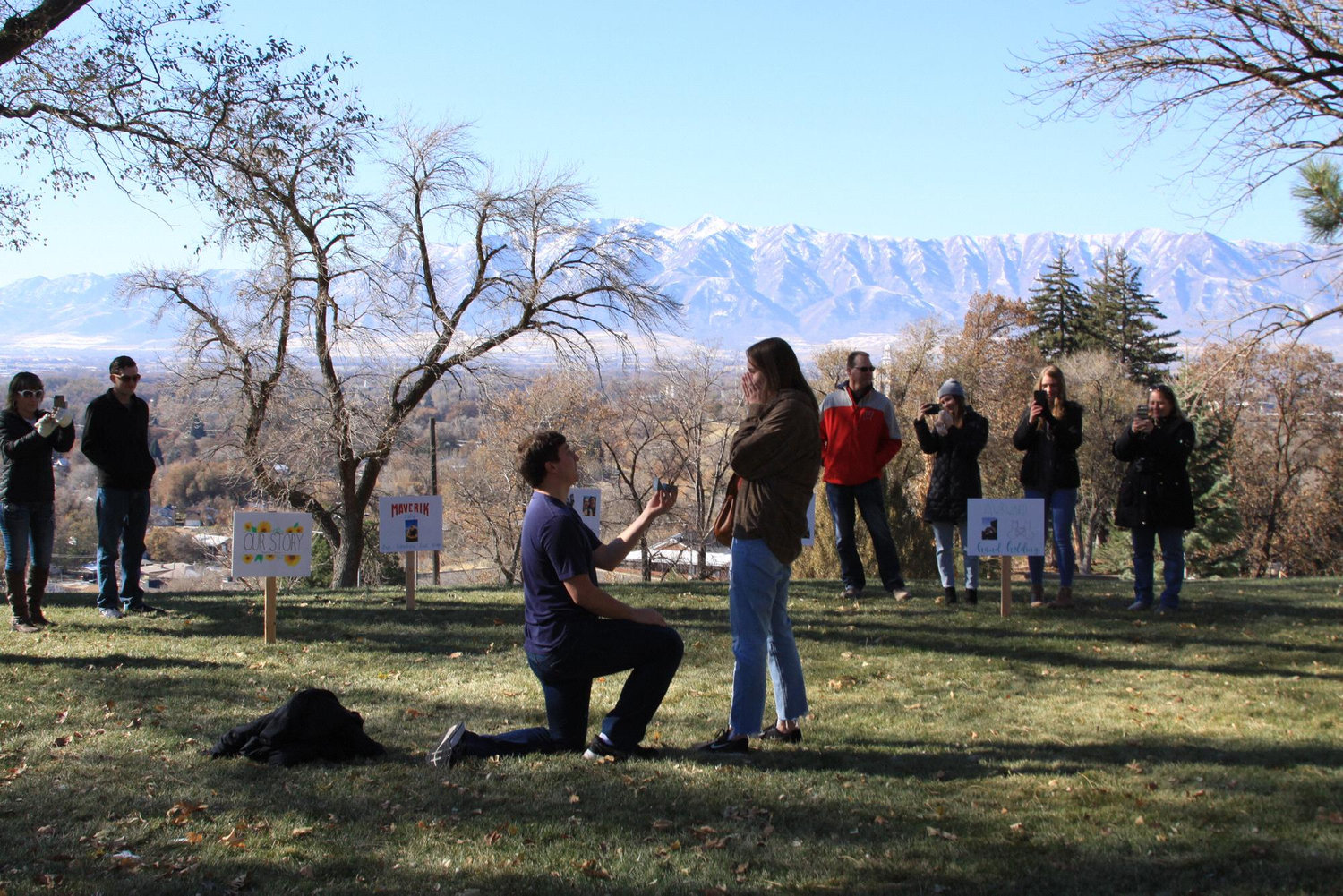 Cade proposing at our "spot" on campus with both our families there. With the help of his sister-in-law, Amber, he had signs about different memories of our relationship all laid out as well!