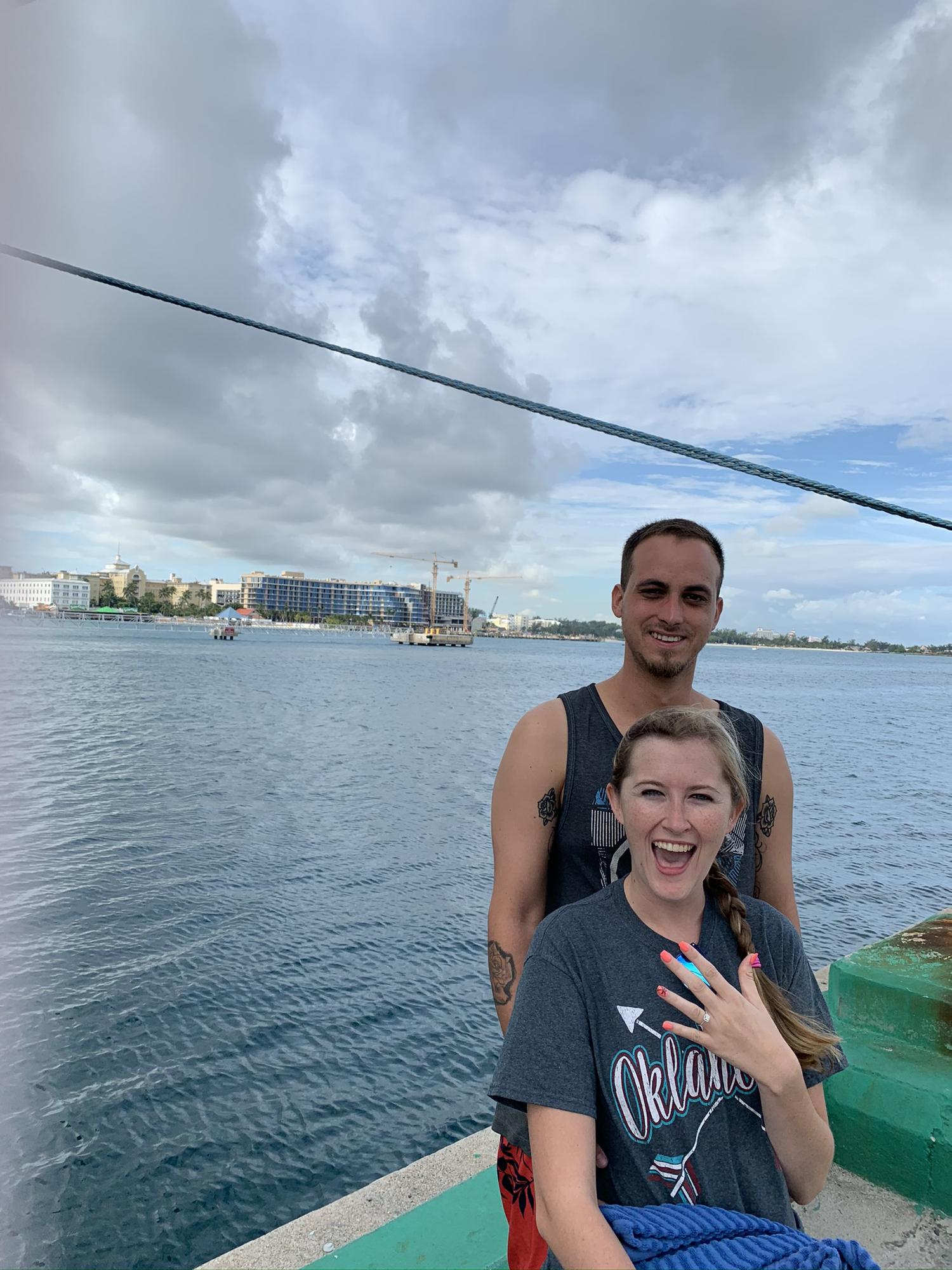 Us posing across from the beach where he proposed
