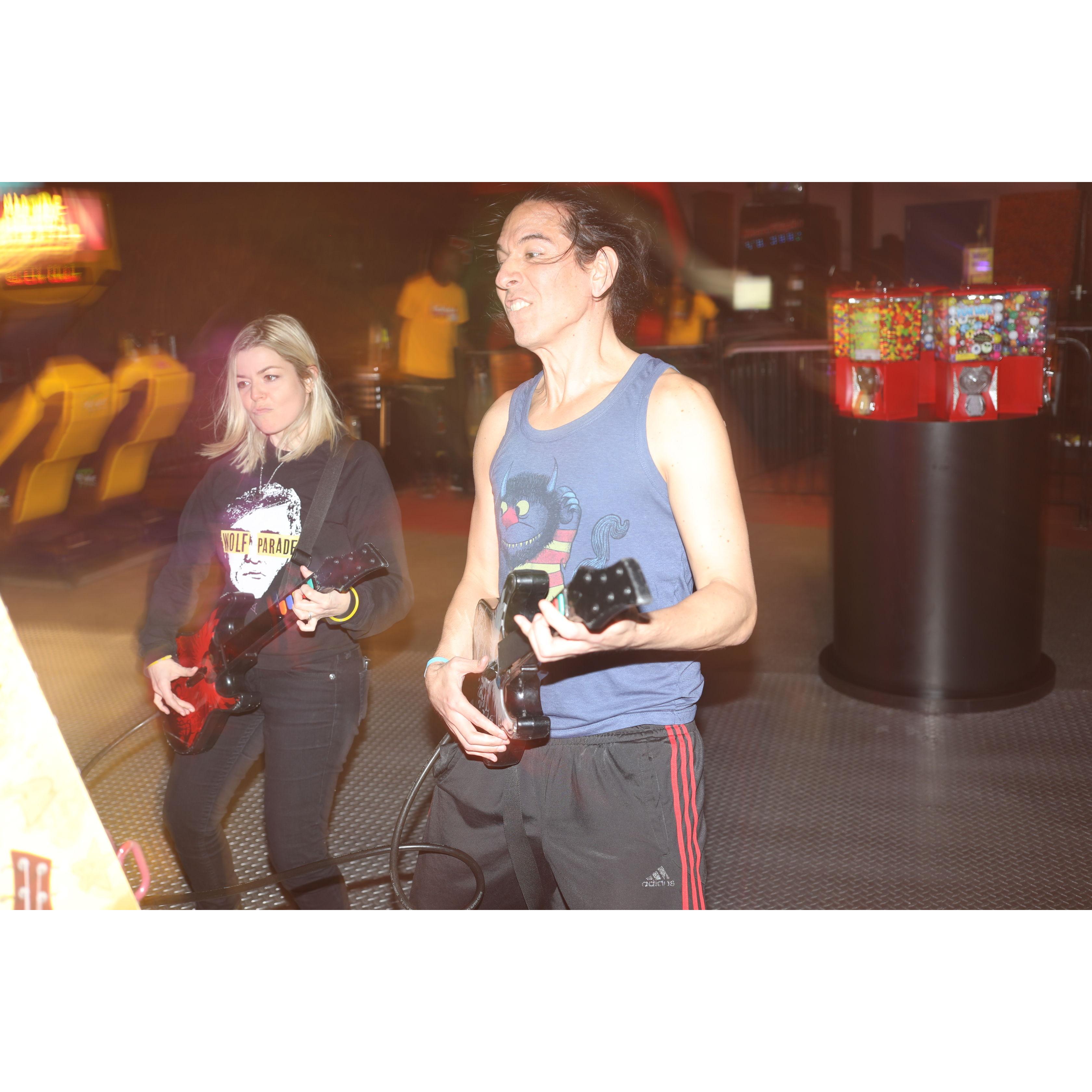 Jason and Alex playing rock band at an arcade.