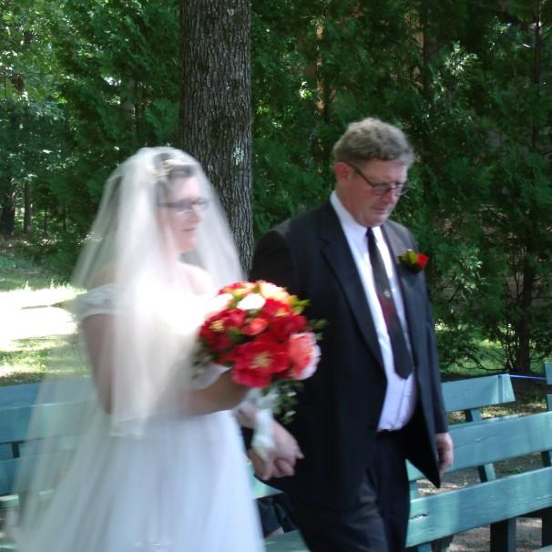 Nancy and her father, David, walking up the aisle of the outdoor chapel.