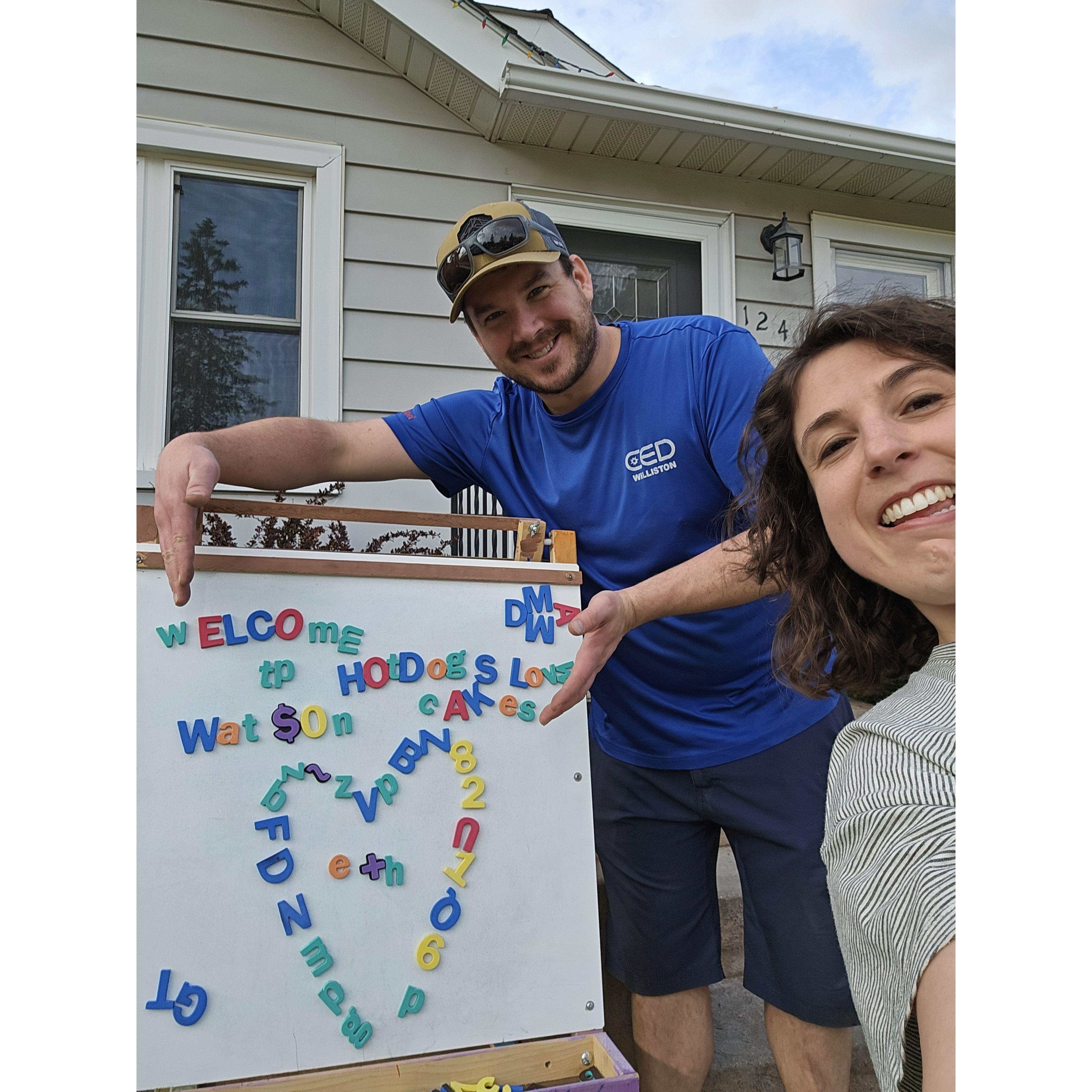 April 2024: In front of our house with a whiteboard Hannah found in the alleyway