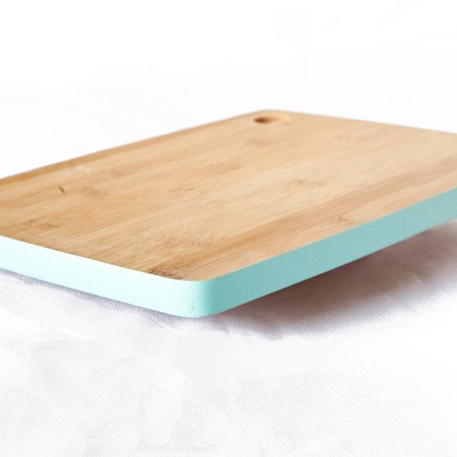 Natural Bamboo Wood Cutting Board with Teal Border. Brings simple elegance to your kitchen. Small-medium size. Cut Out Handle for easy space saving storage.